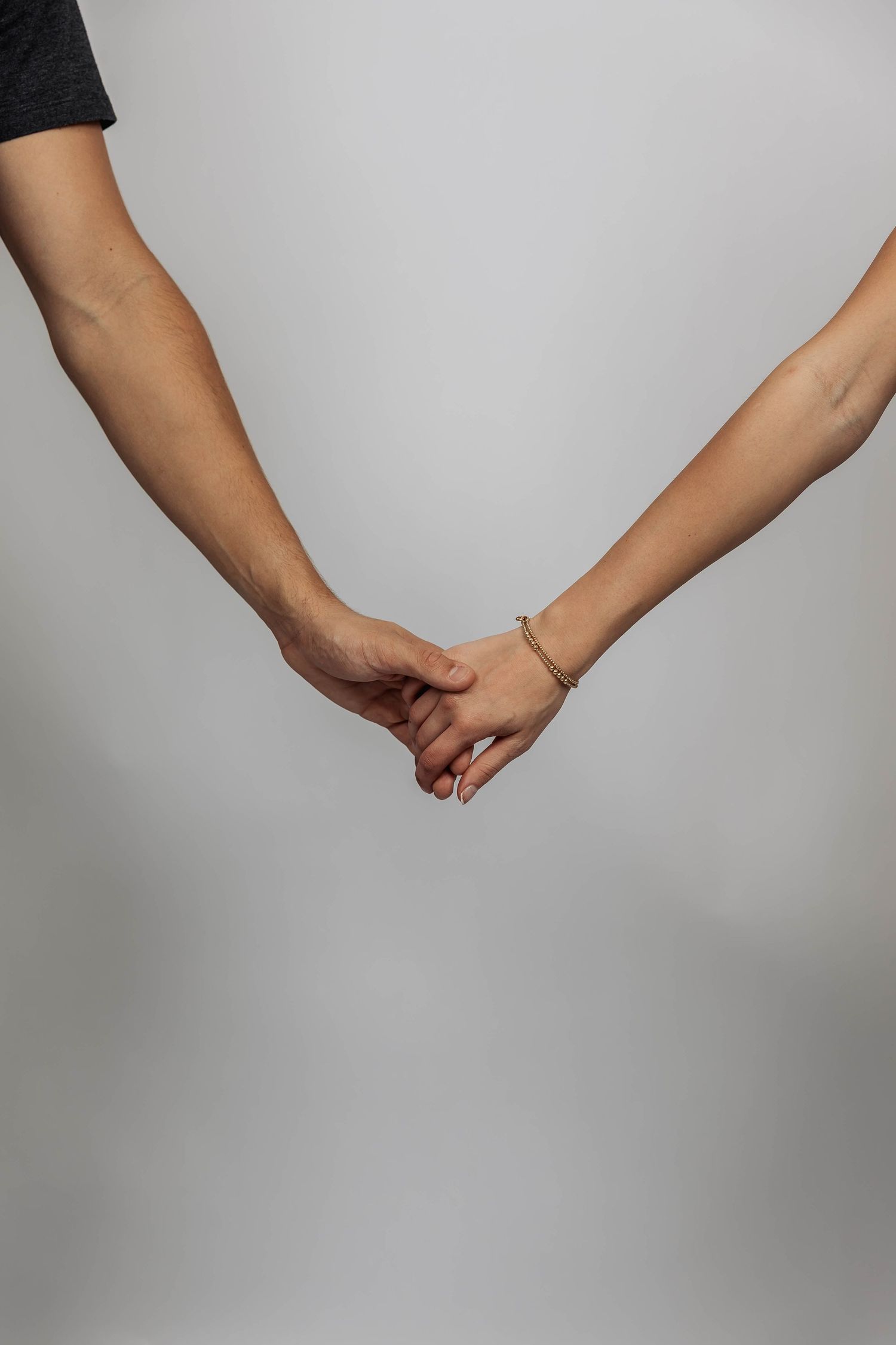 Close-up of hands reaching for each other against white background.