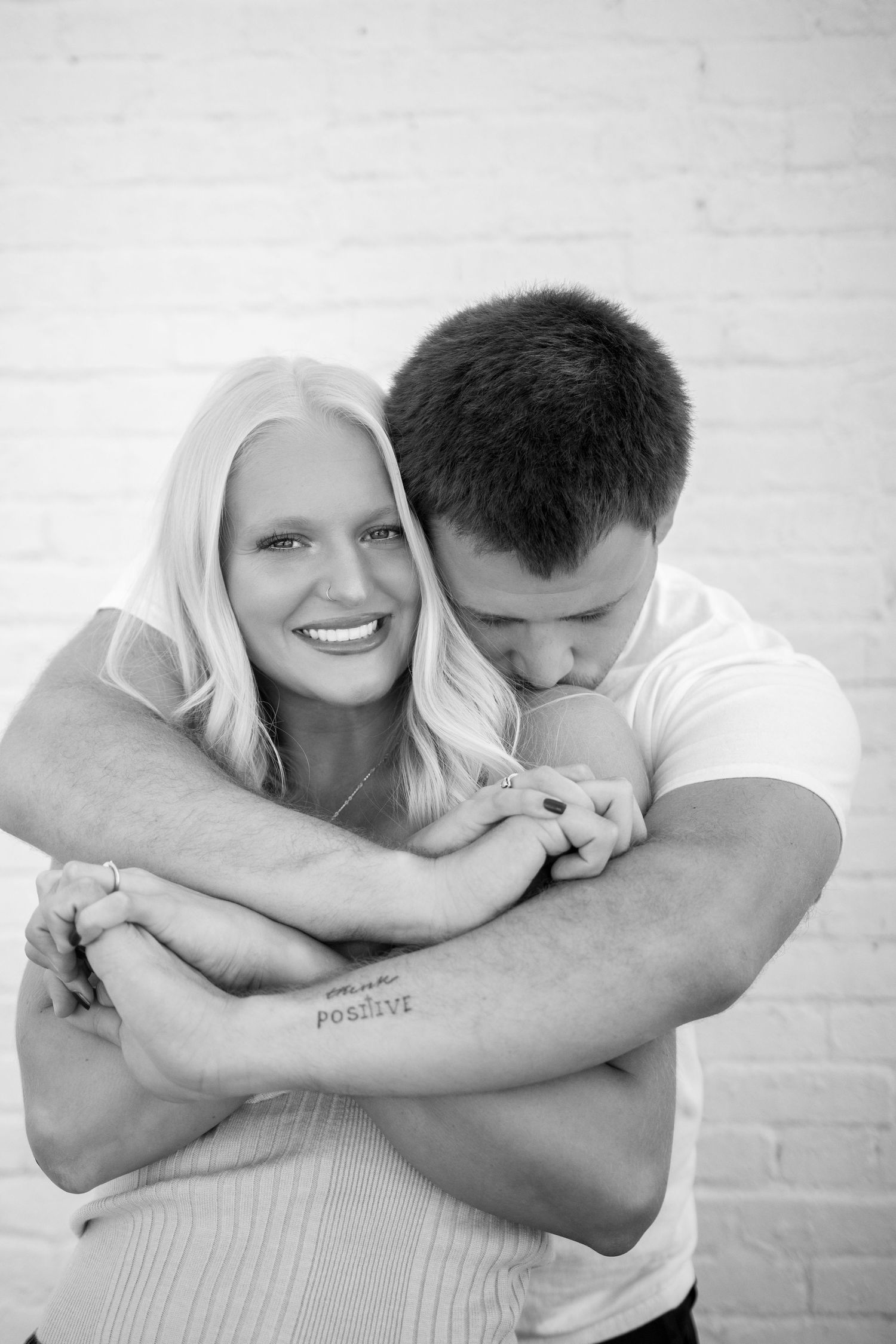 Black and white photo series capturing tender moments between a couple against white wall.