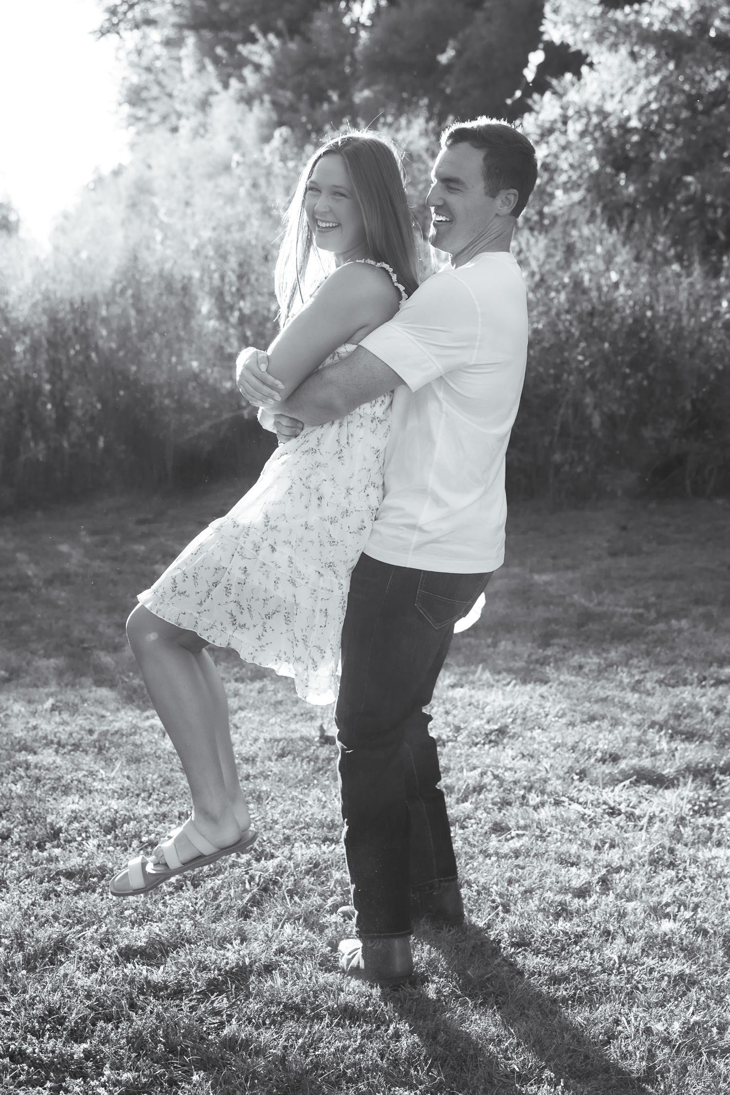 Playful couple dances and spins in sunlit meadow.
