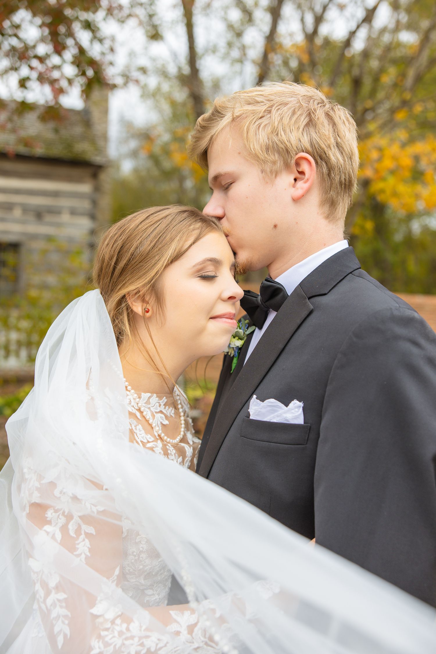 Autumn wedding portraits with bride in lace dress and veil sharing intimate moments outdoors.