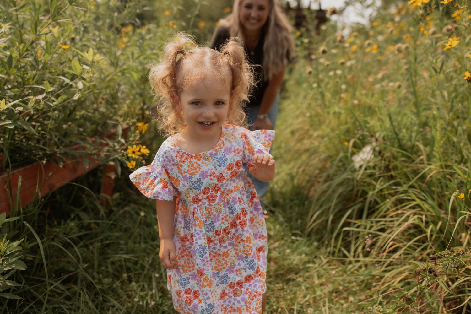 A cheerful scene in a garden with floral dress and yellow wildflowers in the background.
