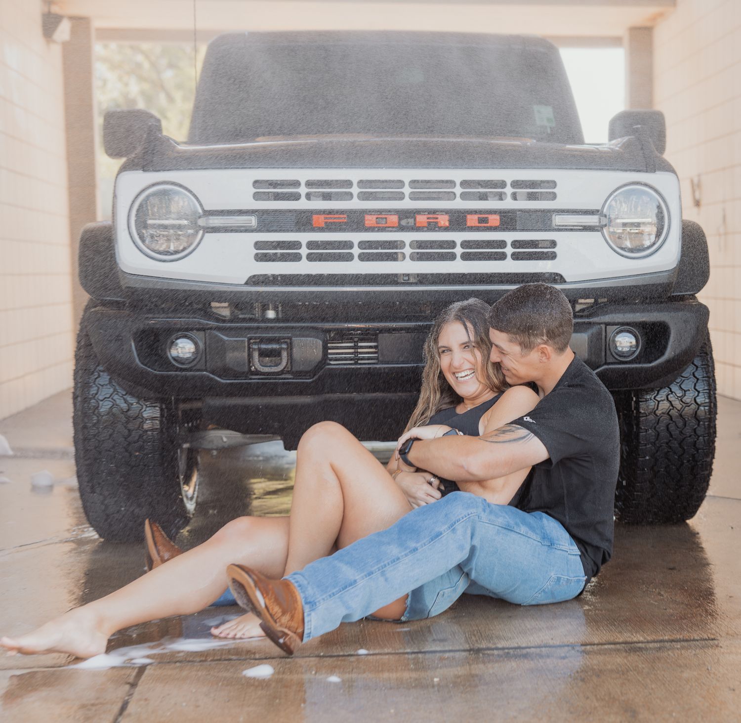 Romantic couple poses playfully in front of parked truck during photo session.