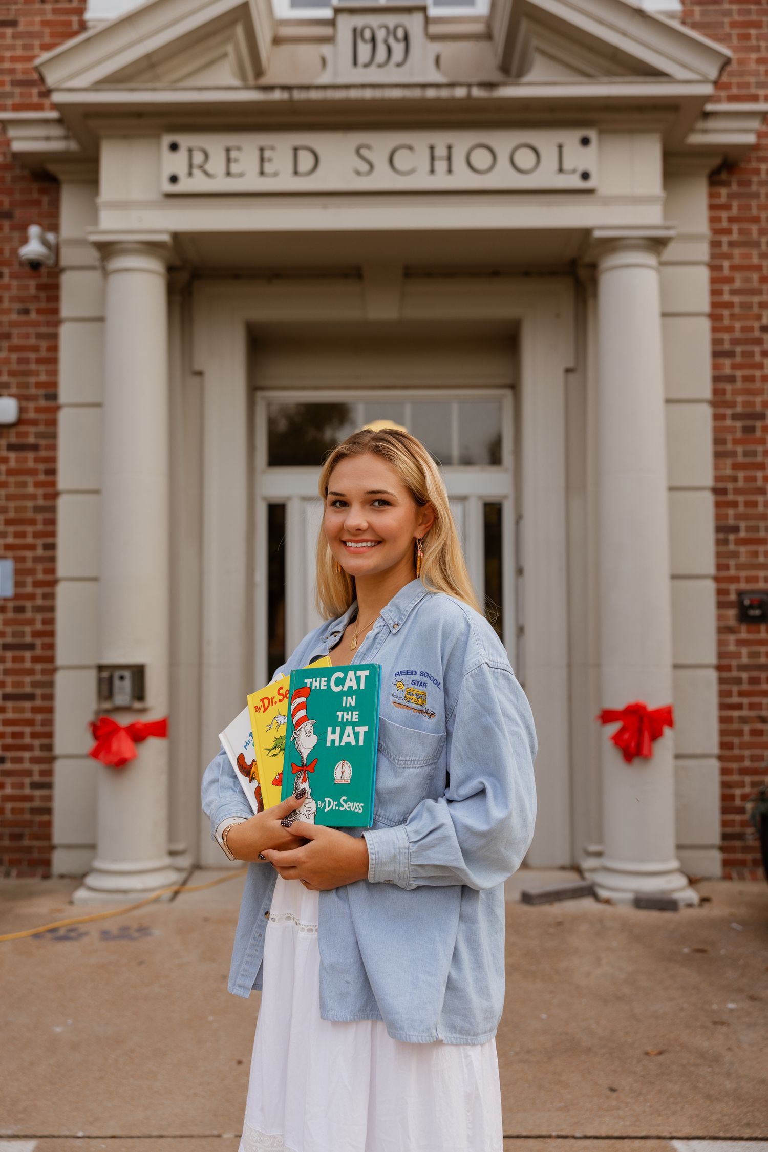 A casual photoshoot featuring Dr. Seuss books takes place at the entrance of Reed School.
