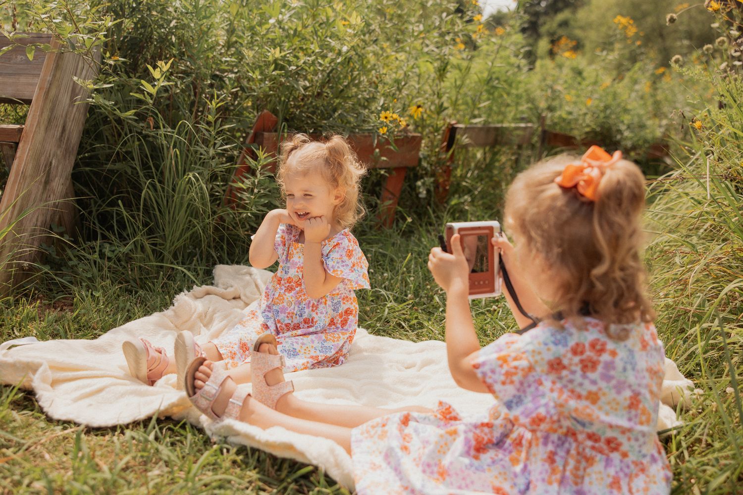 Children in matching floral dresses enjoy a summer picnic while taking pictures.