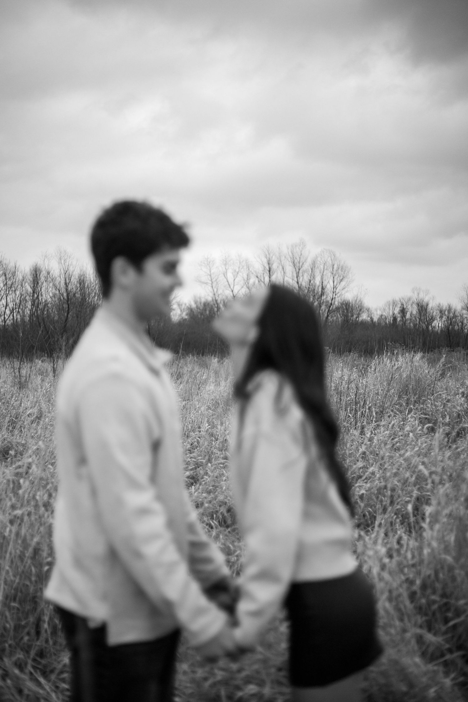 Candid black and white sequence capturing tender moments between a couple in a meadow.