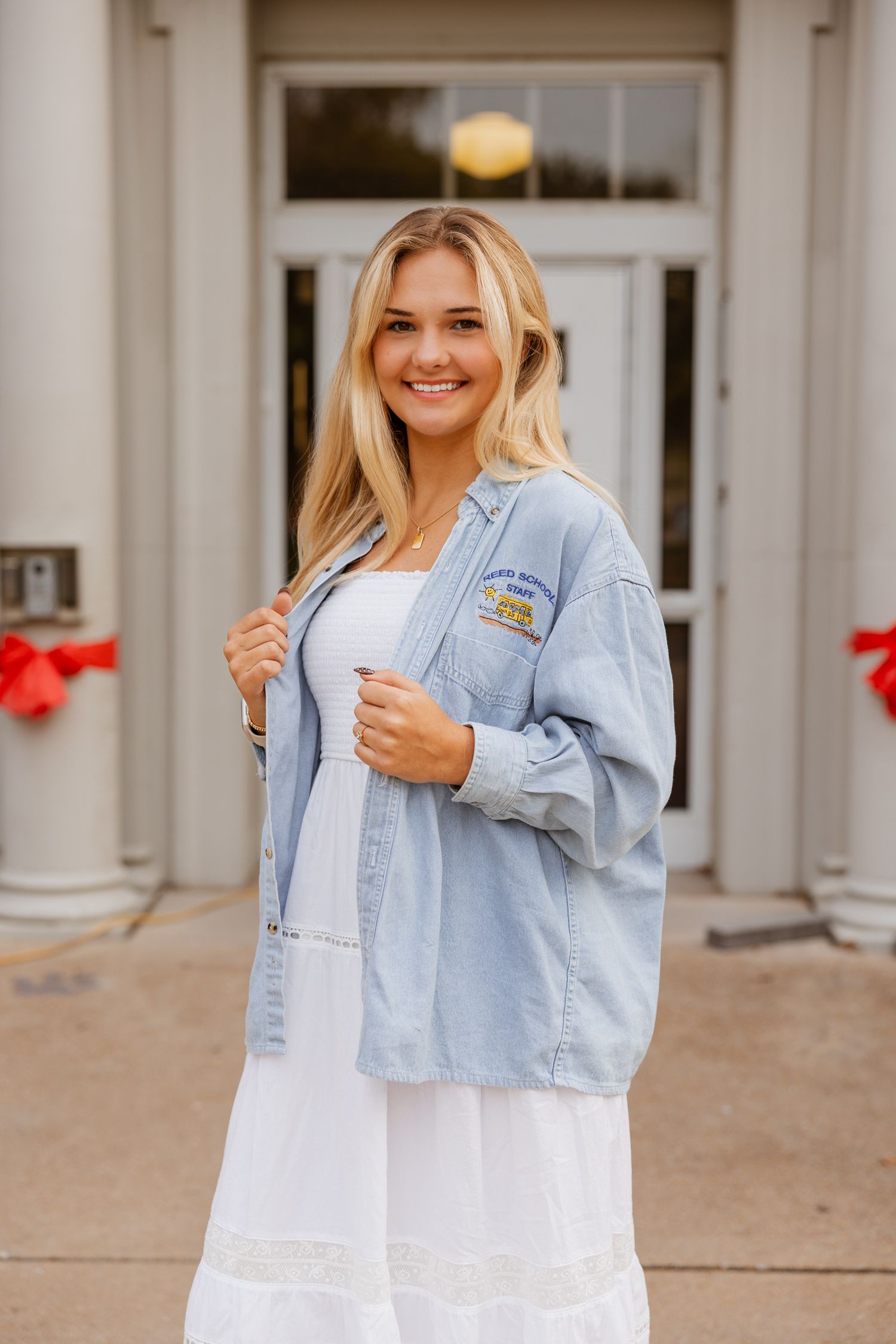 Casual outfit with white dress and light denim jacket shown outside school entrance.