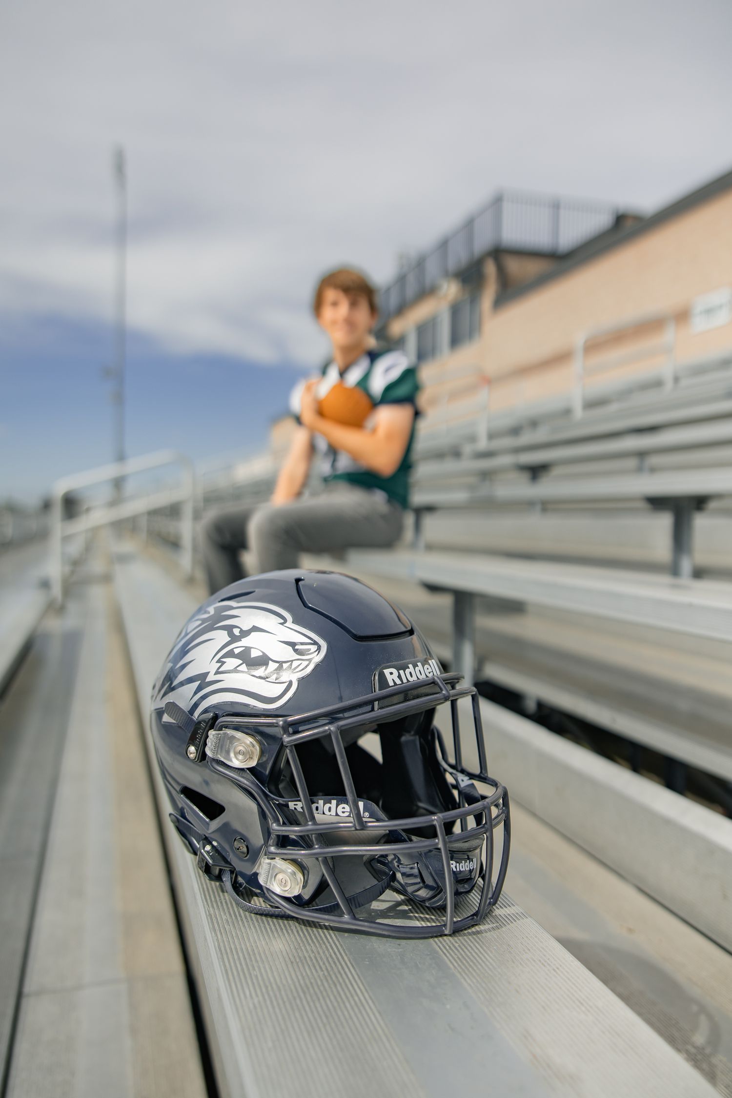 Football helmets lined up on stadium bleachers with blurred background.