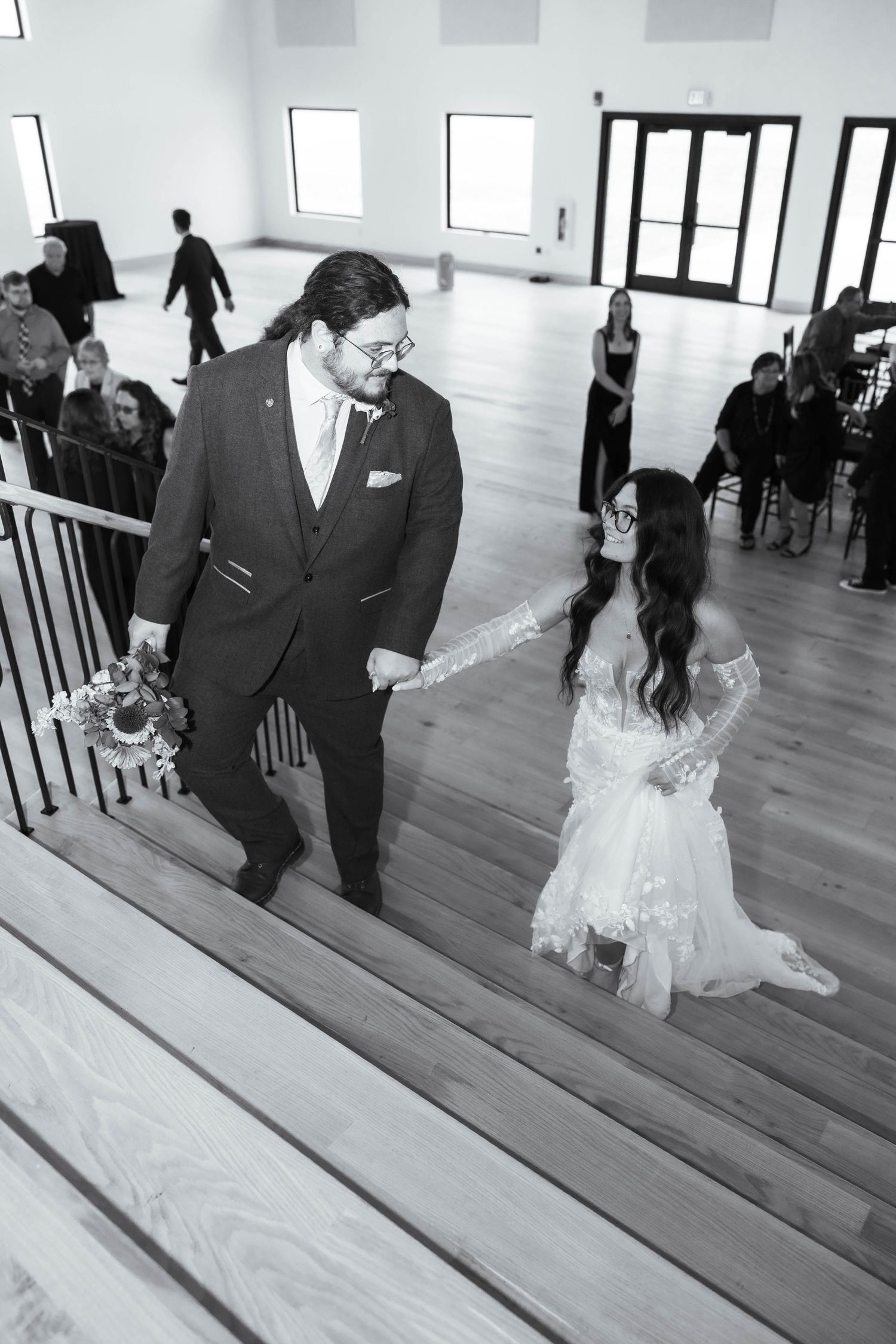 Black and white photo of wedding couple dancing in modern venue with wooden floors.