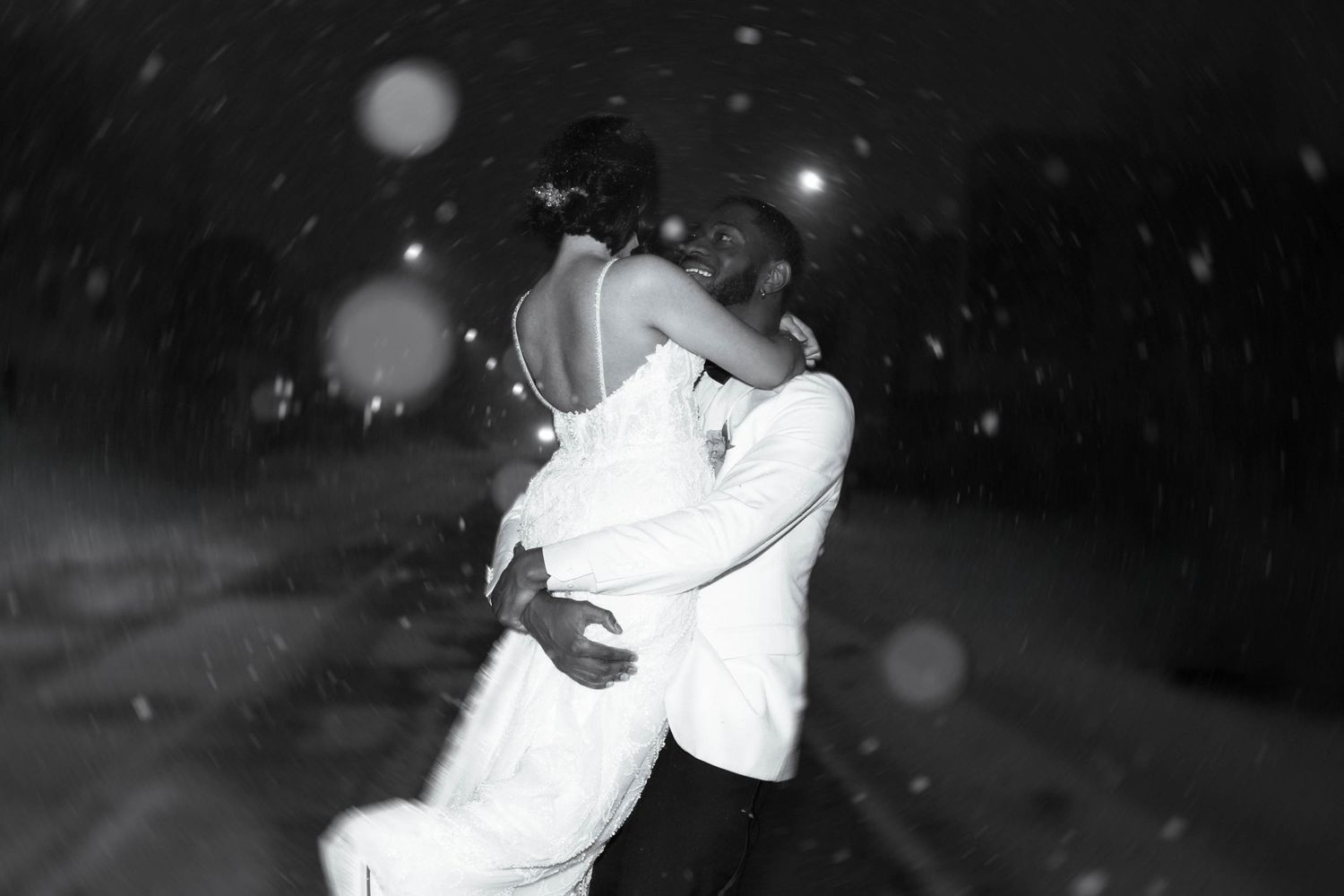A couple dances together at a wedding reception in black and white.