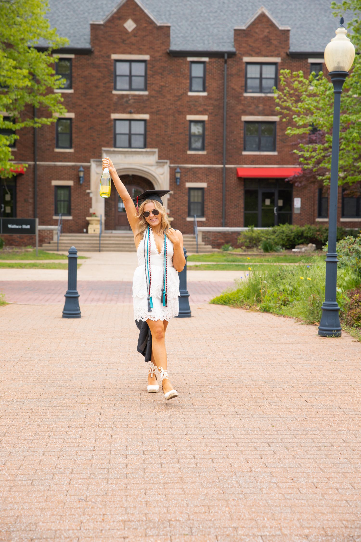 Red brick university buildings and lamp posts line a paved campus walkway.