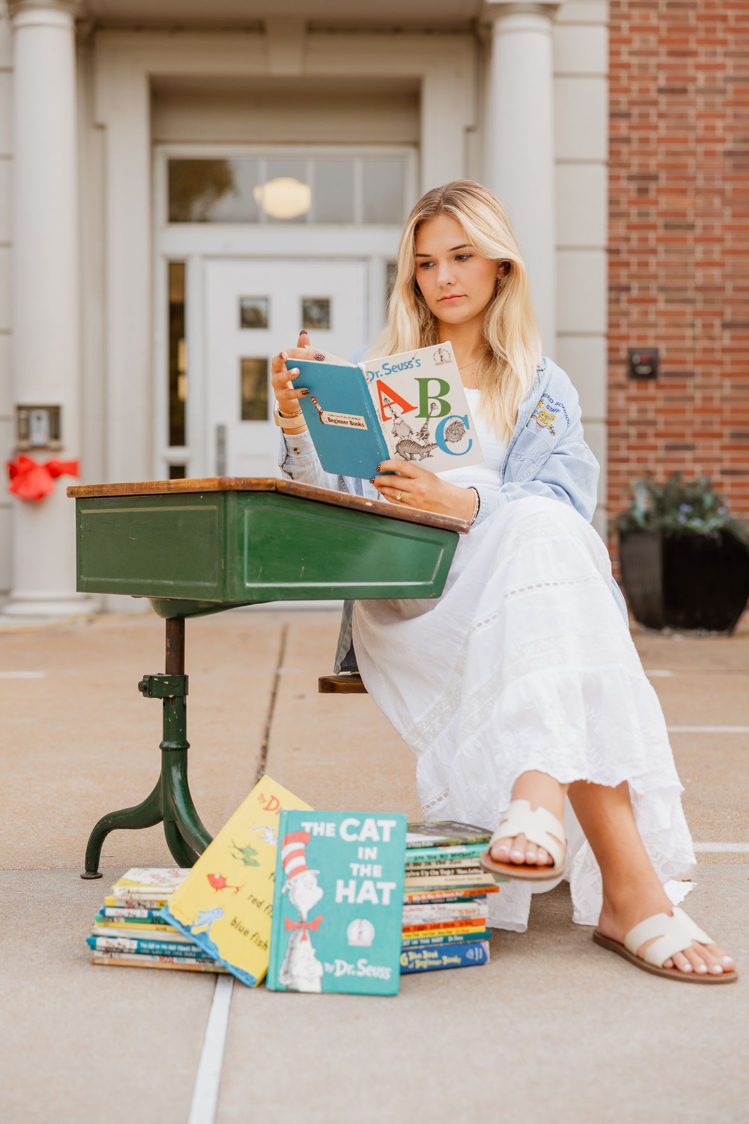 Classic children's books including Cat in the Hat displayed on green vintage desk outside school.