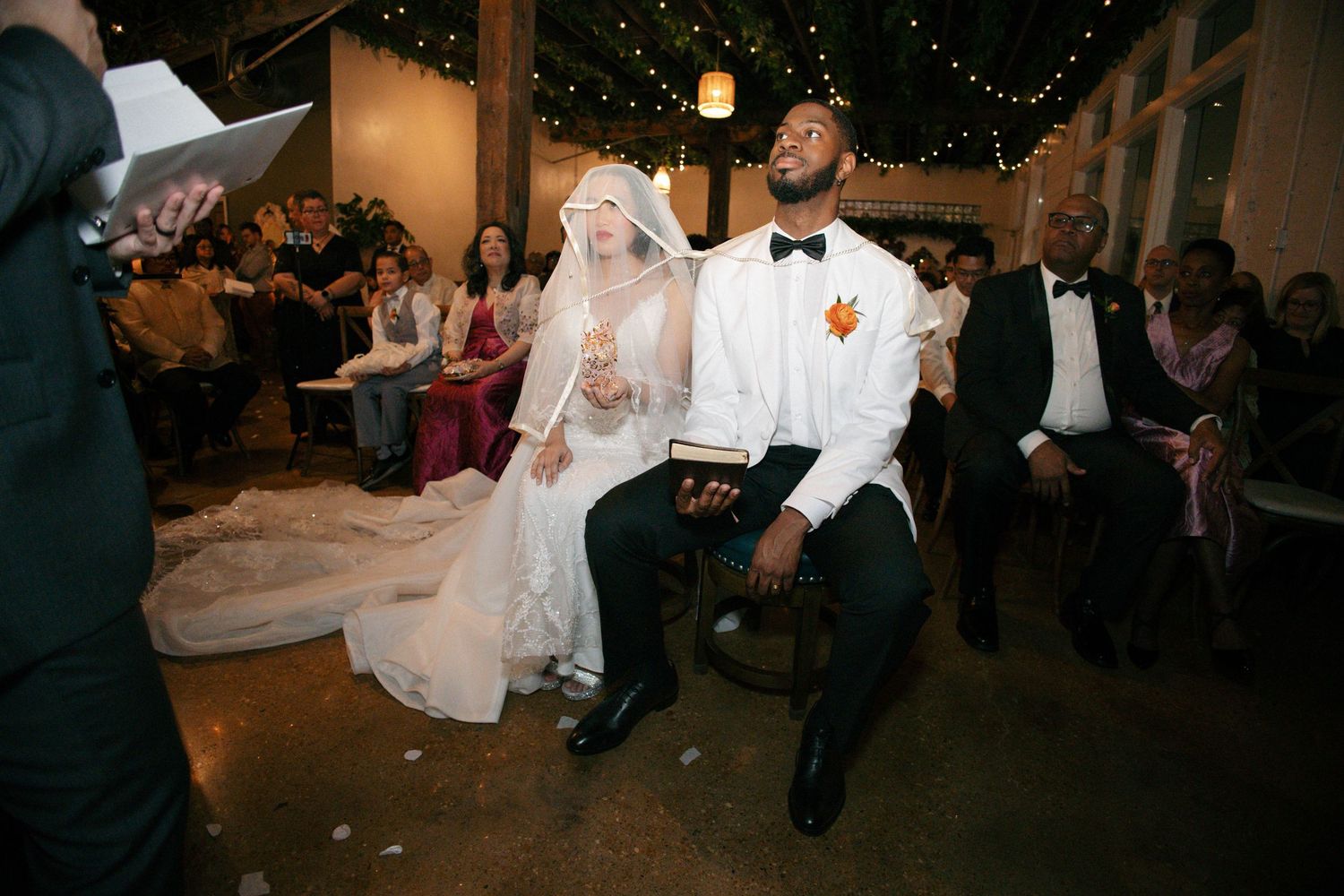 Lively wedding reception dance moment with decorative string lights overhead.