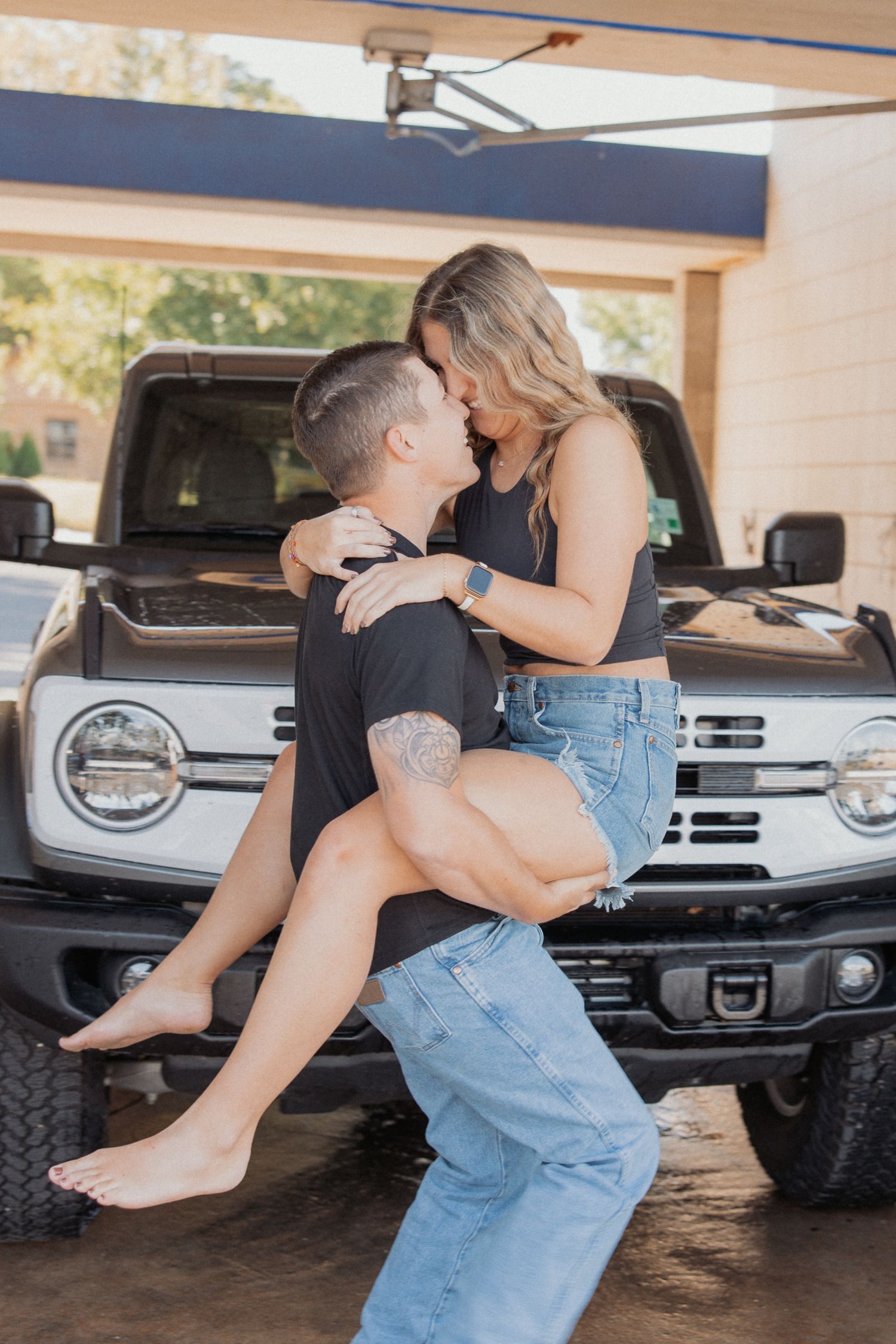 Couple sharing intimate moments in front of a Ford truck in a covered parking area.
