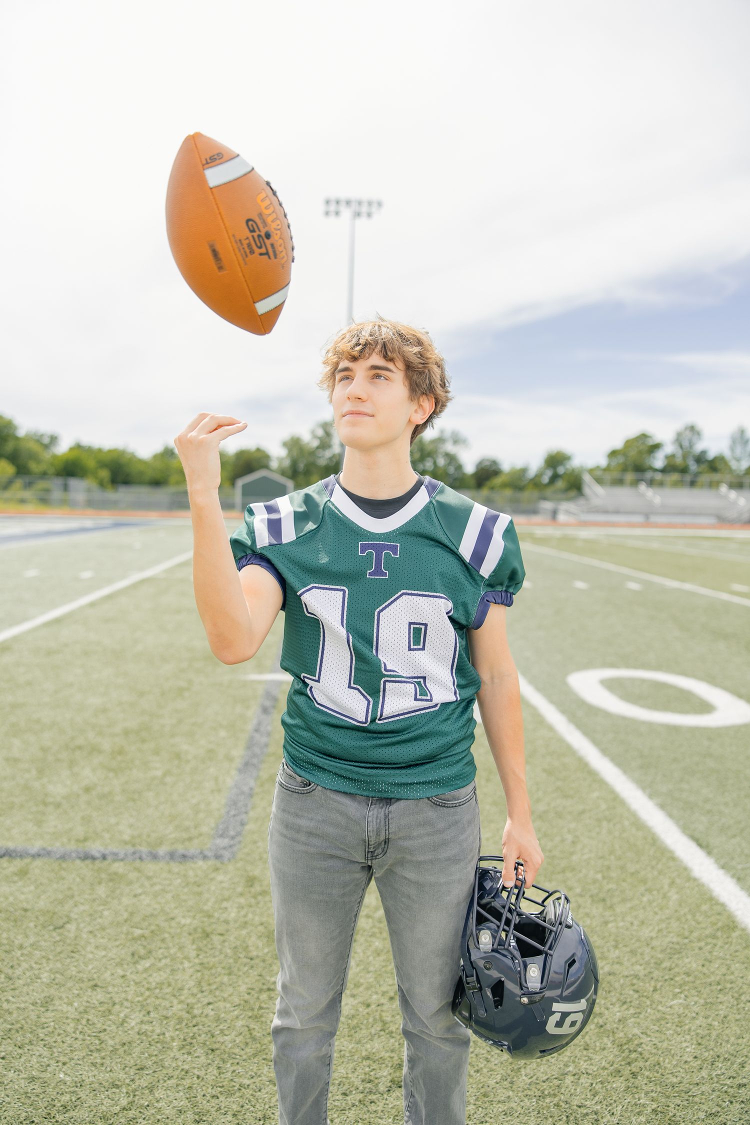 Player in green jersey number 14 practicing football drills on field.