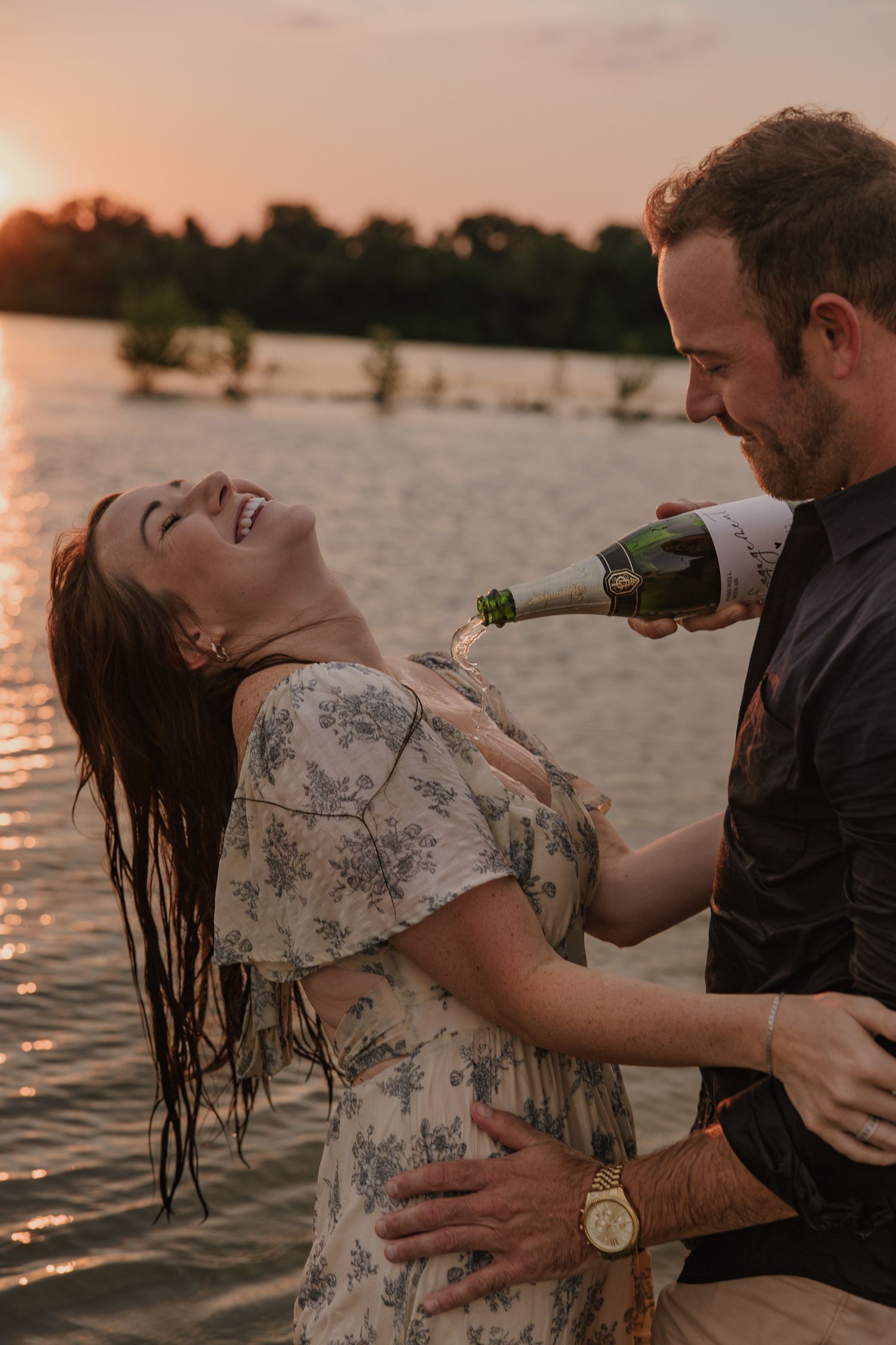 Couple playing with water during sunset lakeside photography session.