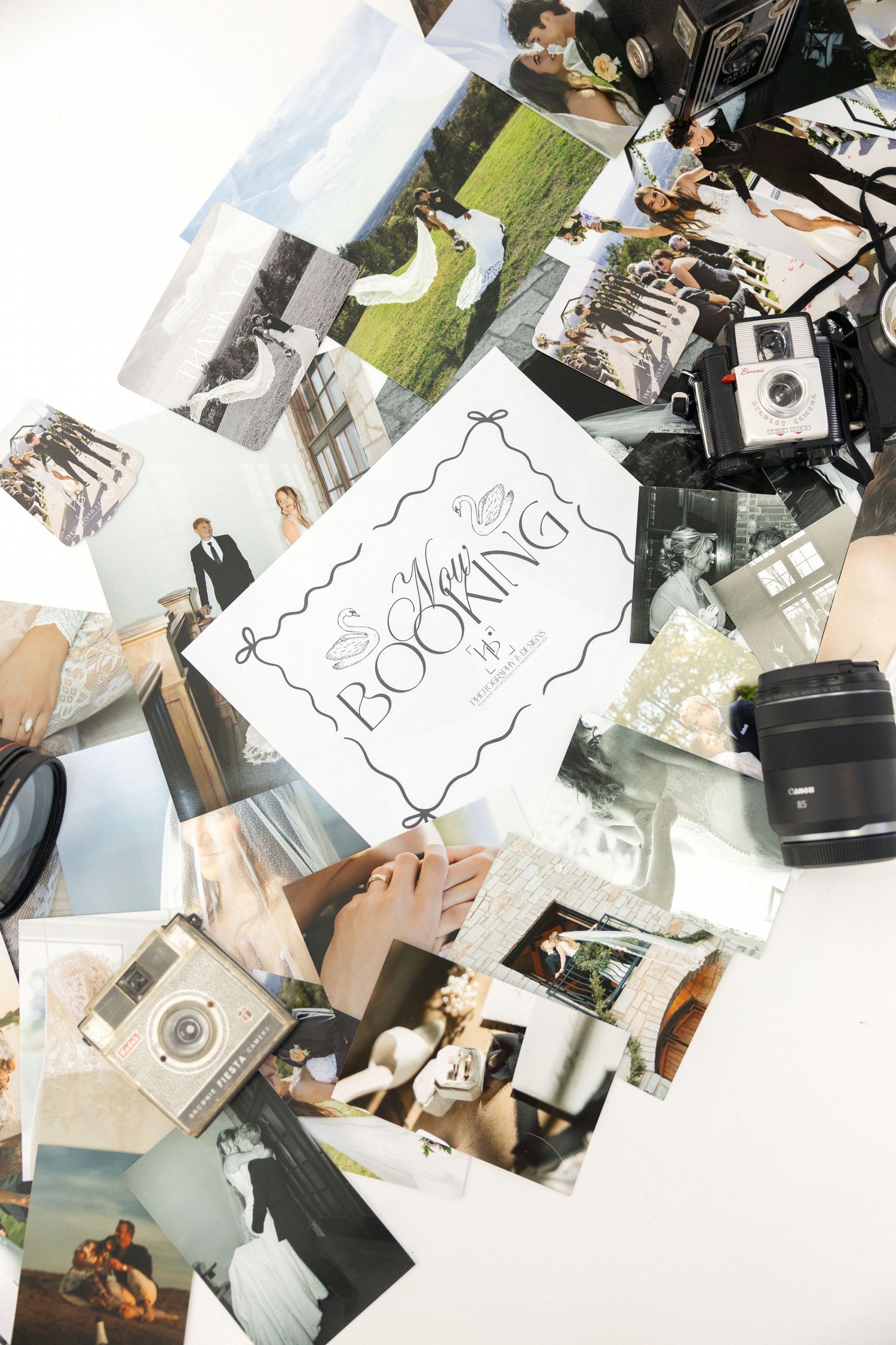 Wedding photos and cameras scattered on white surface with a booking card centerpiece for photography services.