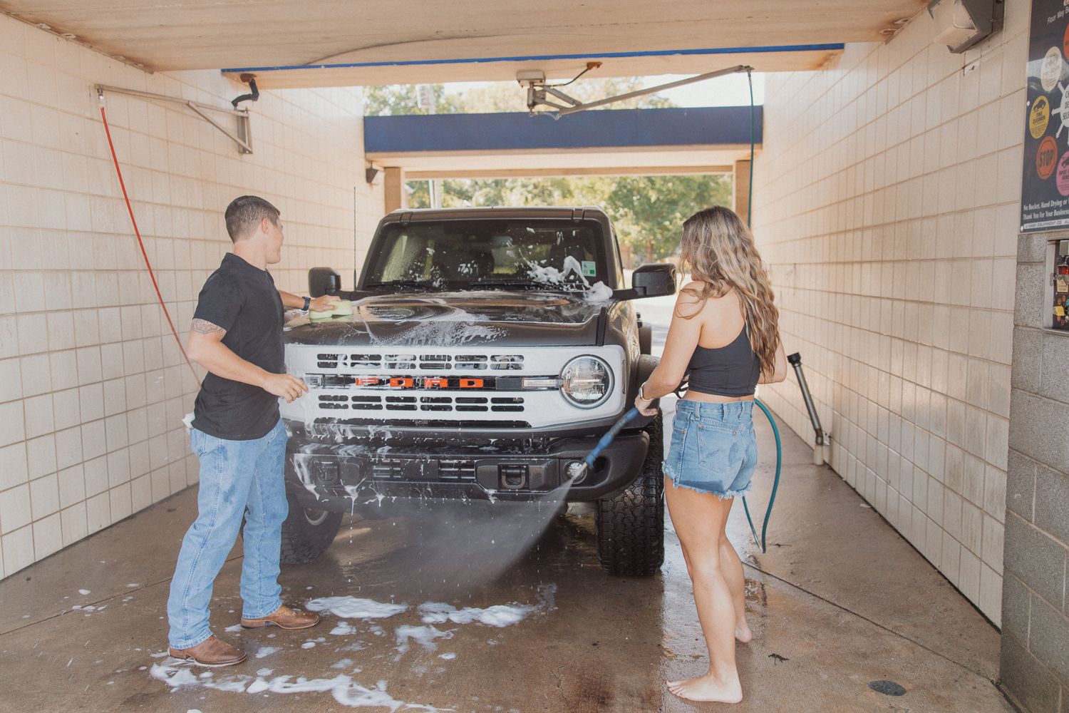 A couple poses together in a covered parking area with a silver truck in the background.