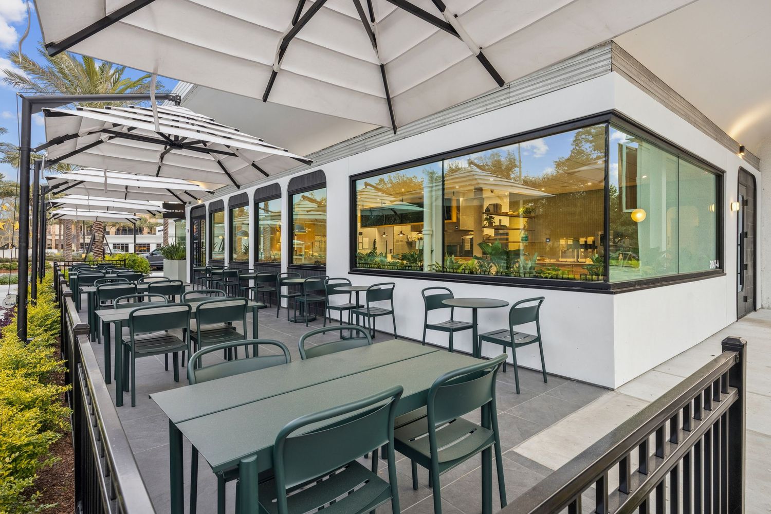 Covered outdoor patio area with green furniture and glass roof panels.