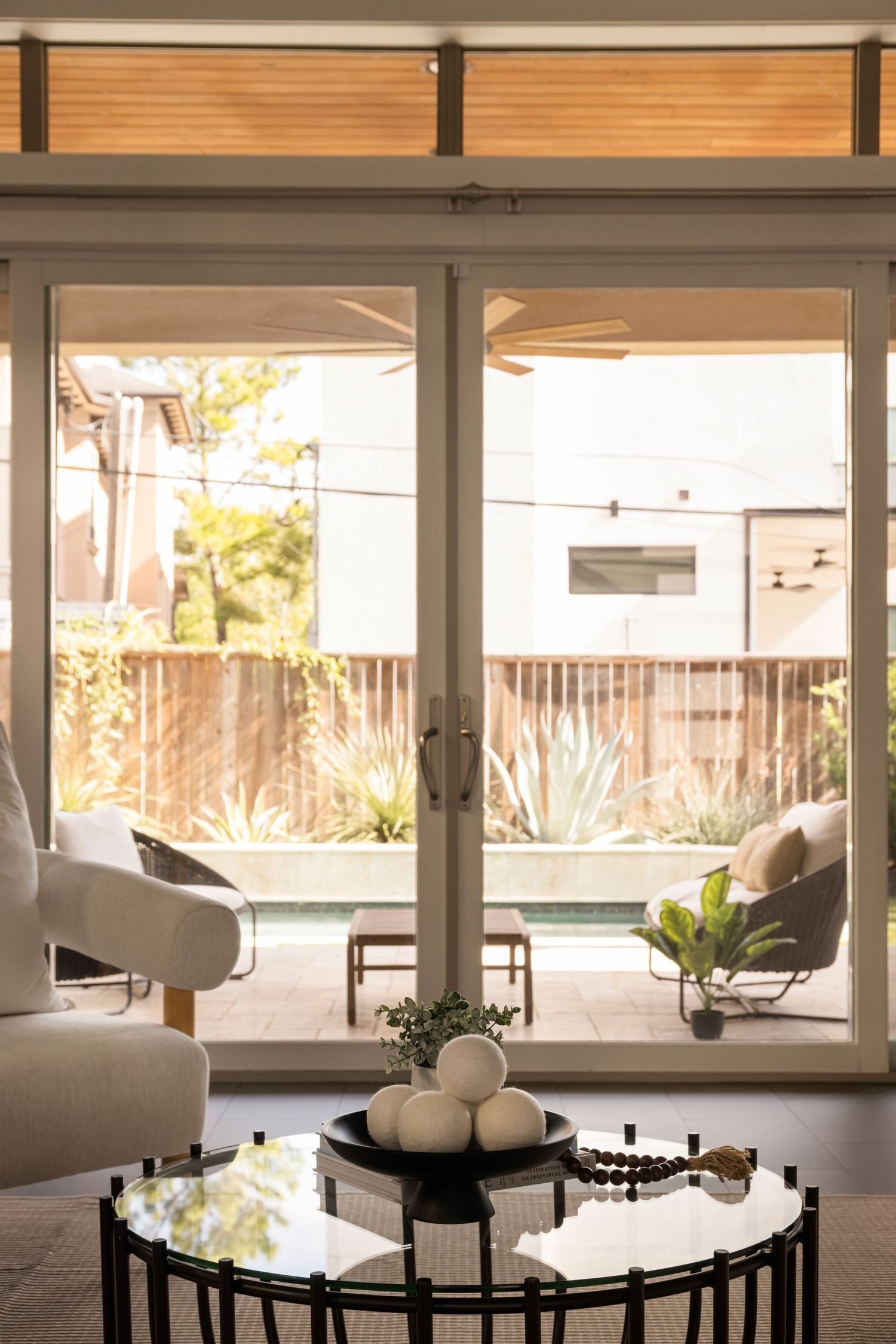 Bright living area with floor-to-ceiling windows, white seating, and natural light flooding the space.