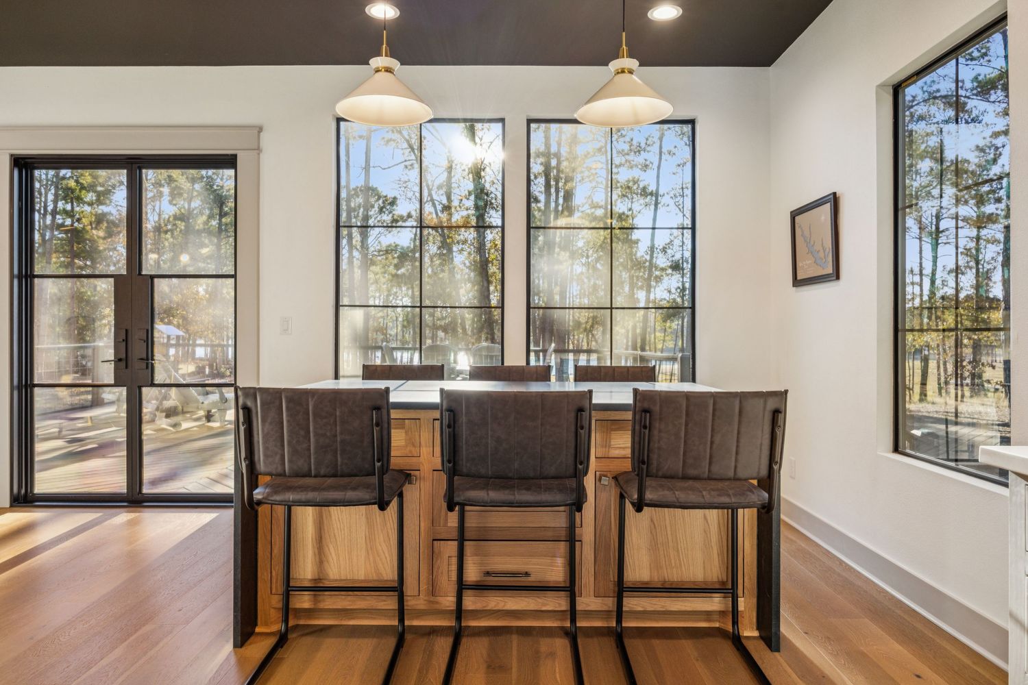Open concept dining area with large windows and dark wood furniture against white walls.