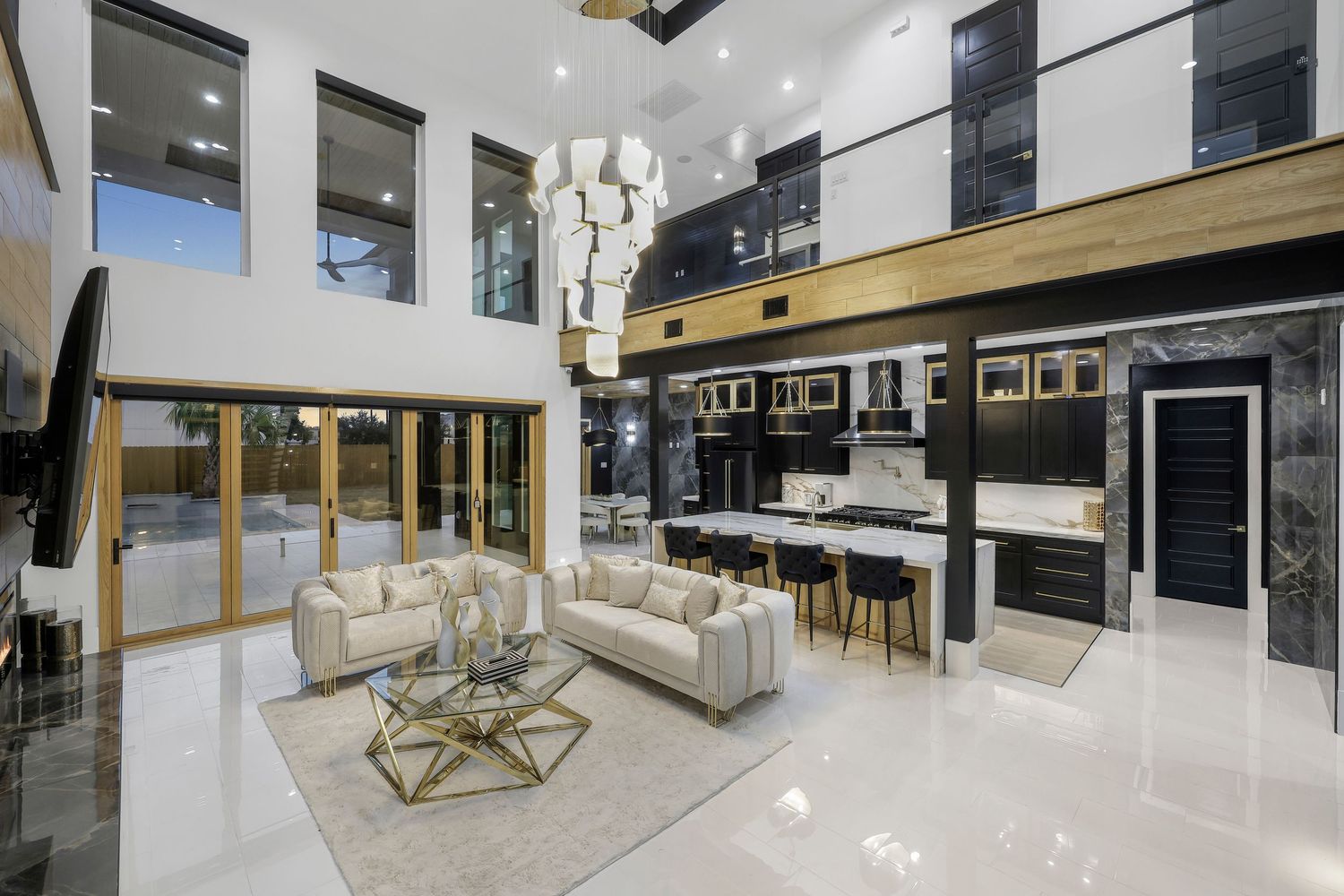 Contemporary open-concept living room with double-height ceilings and gold accents featuring white modern furniture.