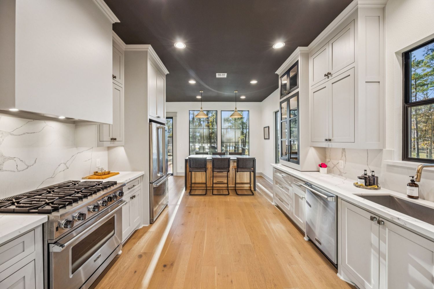 Modern white kitchen with sleek cabinetry, dark countertops, and stainless steel appliances.