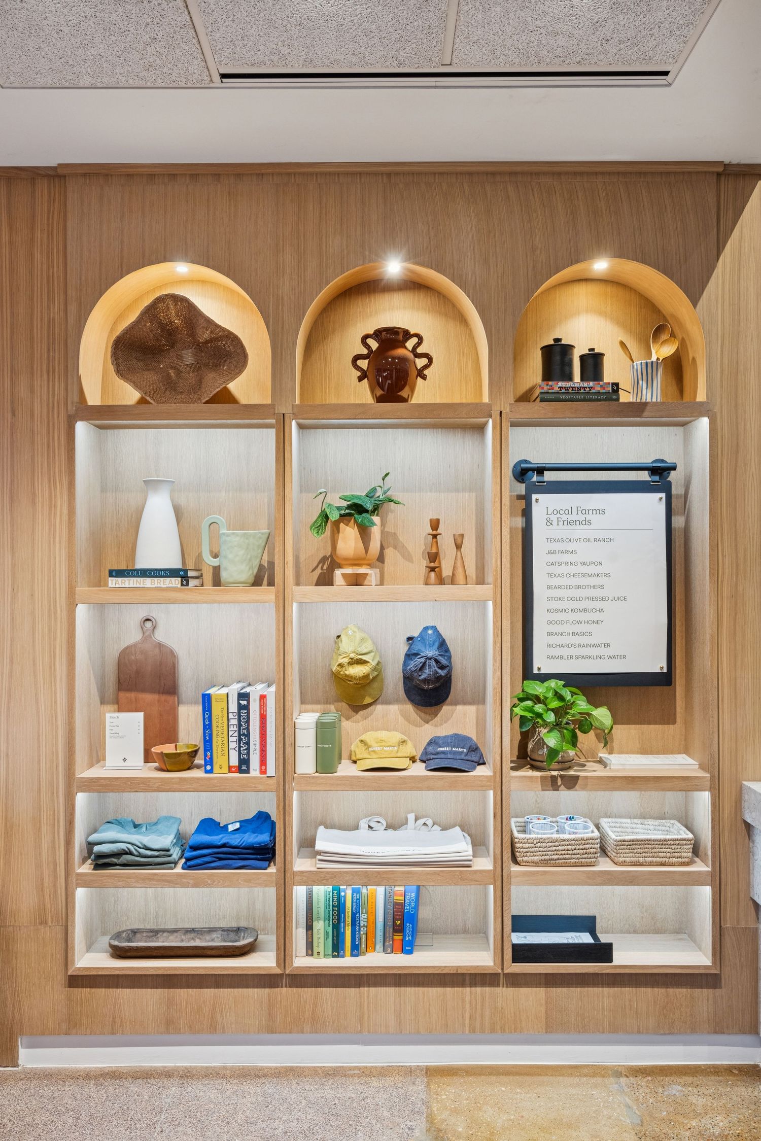 Built-in wooden shelving unit displaying decorative items, books, and plants with modern lighting.