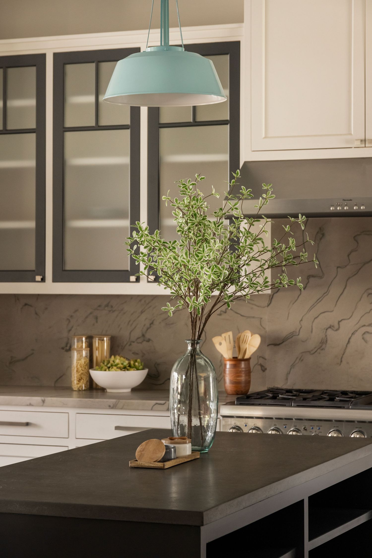 Kitchen detail showing mint pendant light over dark countertop with decorative glass vase.