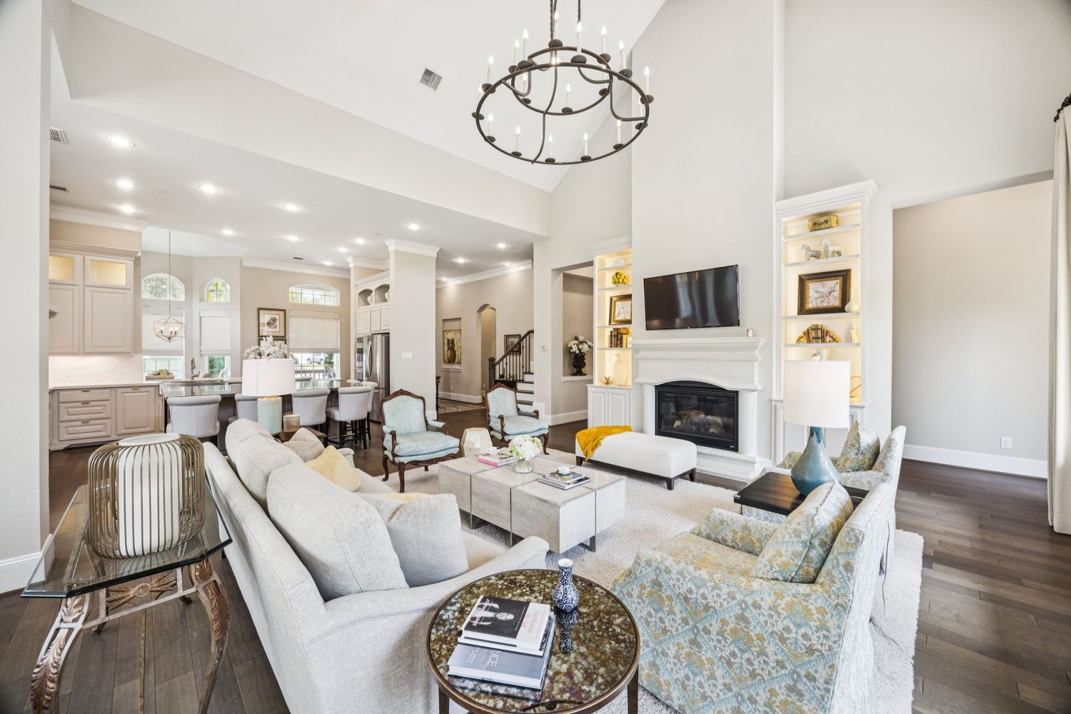 Elegant living room with vaulted ceilings, chandelier, and contemporary furnishings in neutral tones.