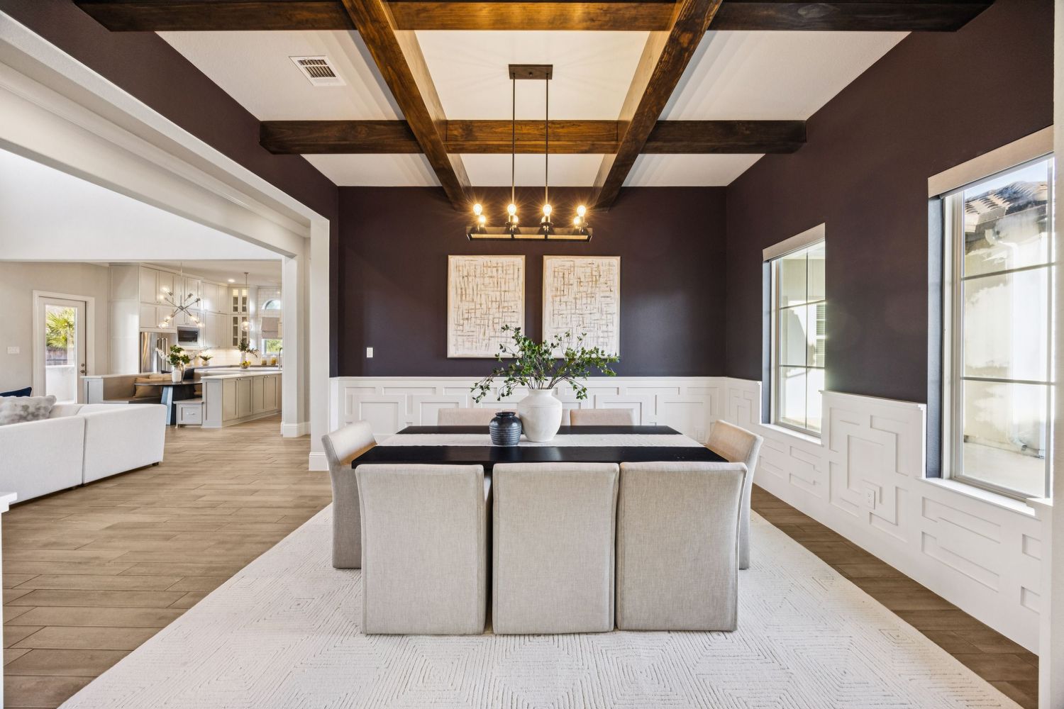 Contemporary open concept living space with exposed wooden beams and modern lighting fixtures.