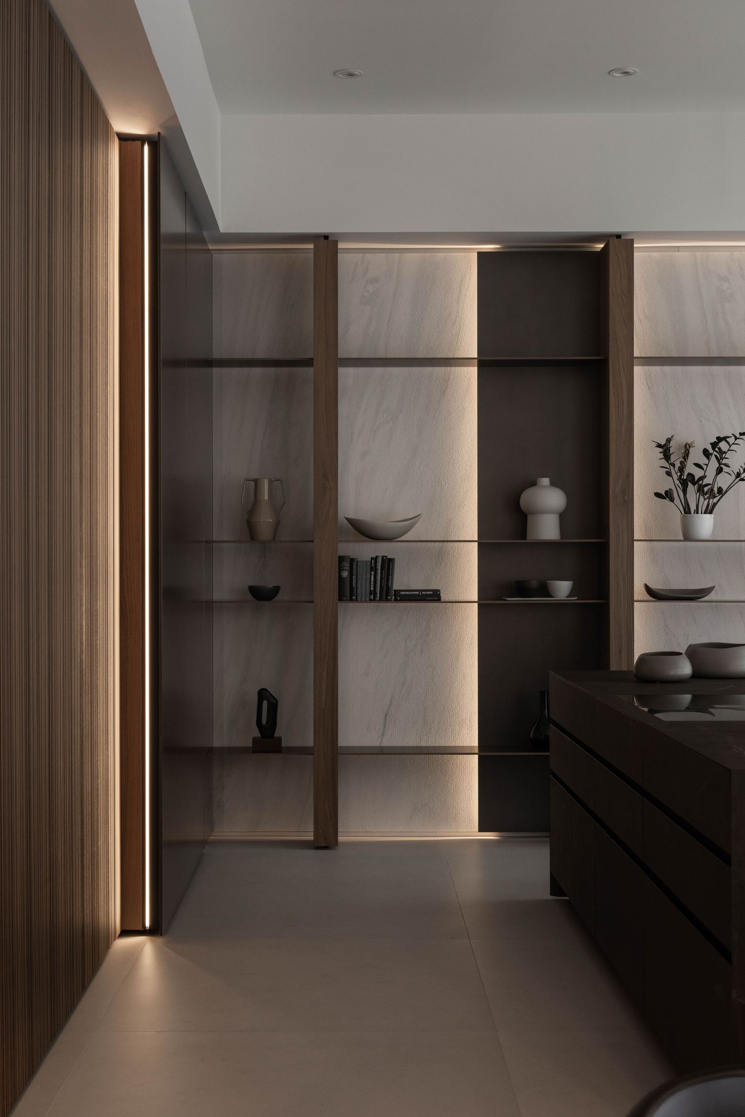 Modern interior with wooden shelving units featuring built-in lighting and minimalist decor displays.