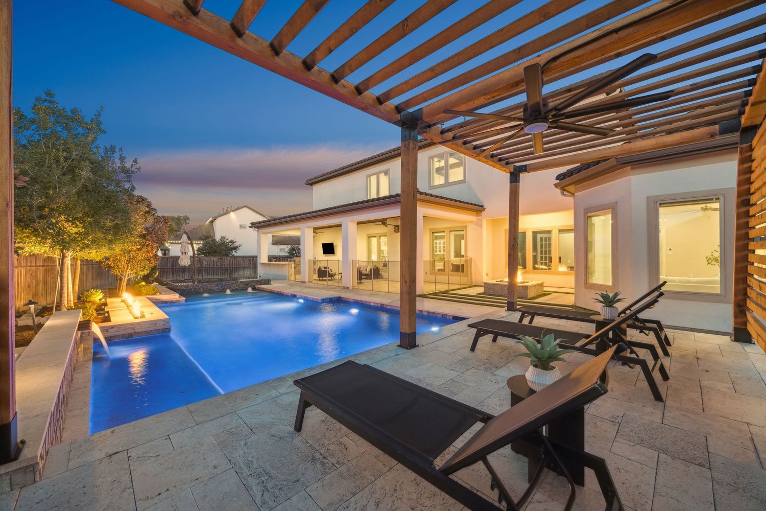 Modern backyard patio with wooden pergola and comfortable seating area overlooking pool.