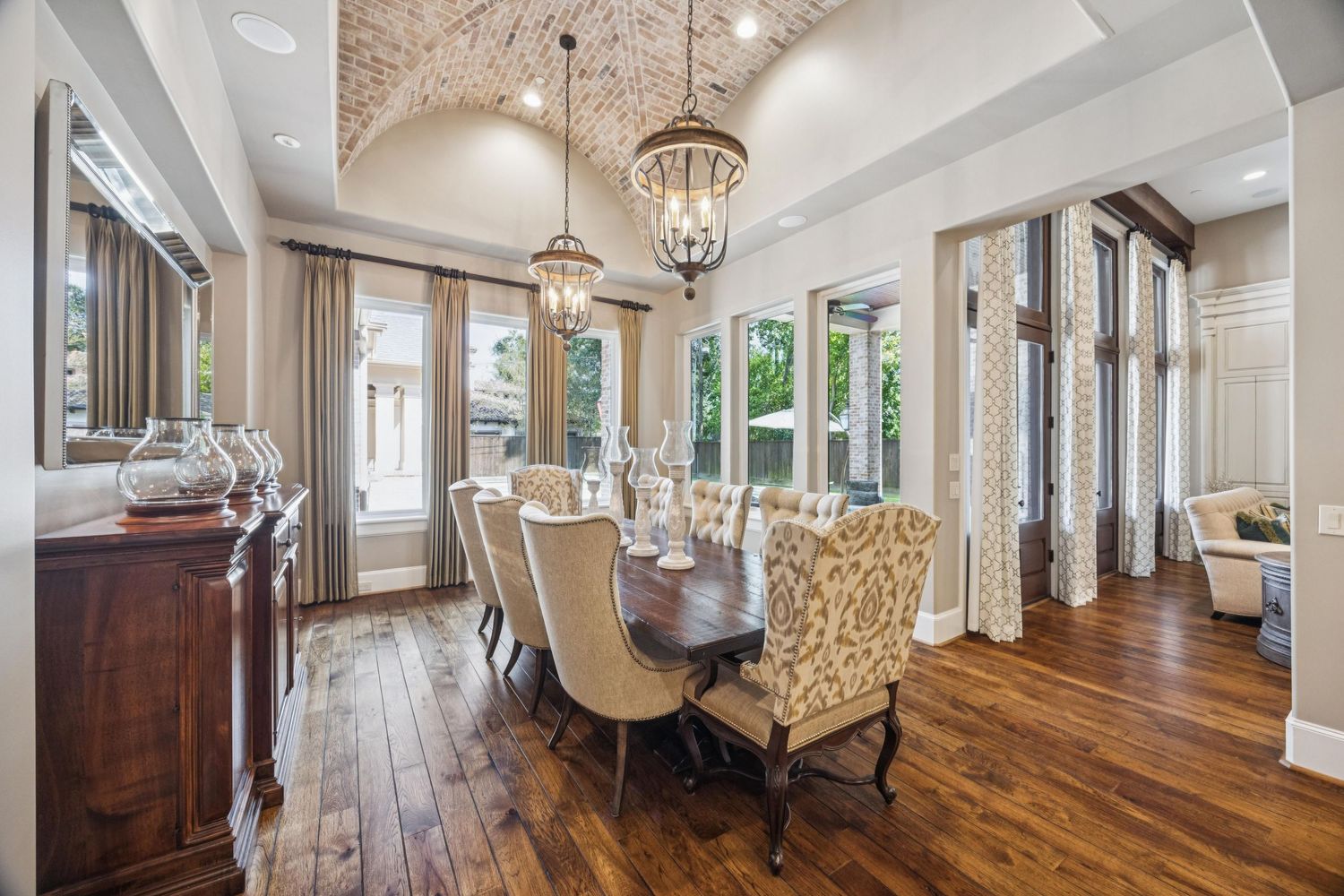 Open concept living area with hardwood floors, exposed beams, and elegant chandeliers.
