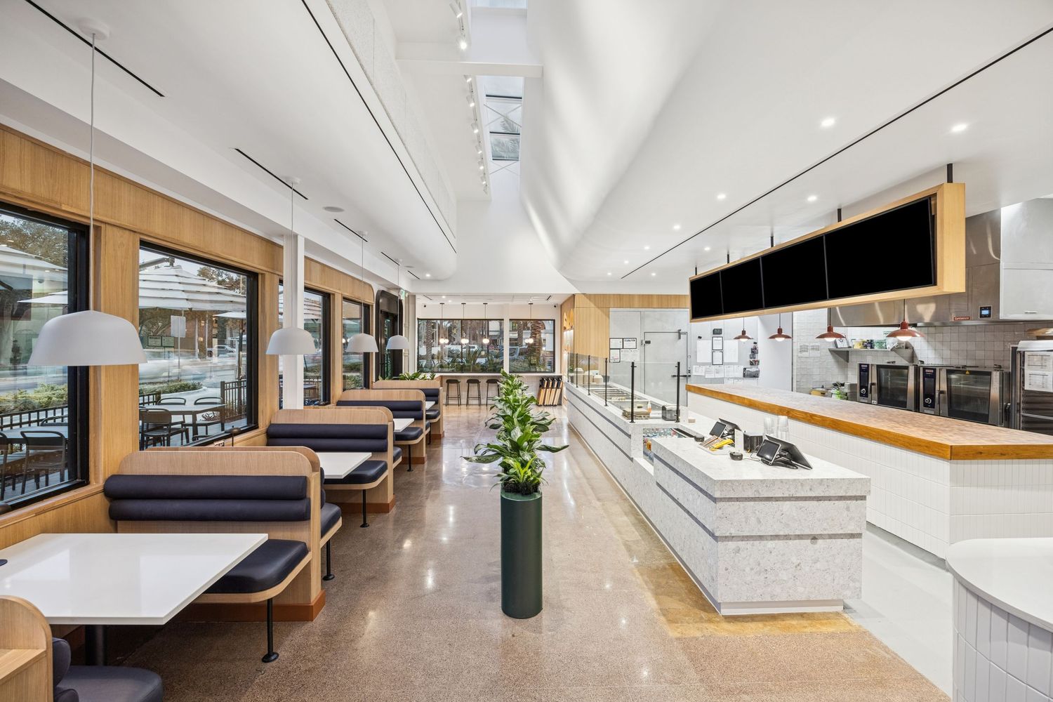 Spacious modern kitchen with vaulted ceiling, wooden accents, and island seating.