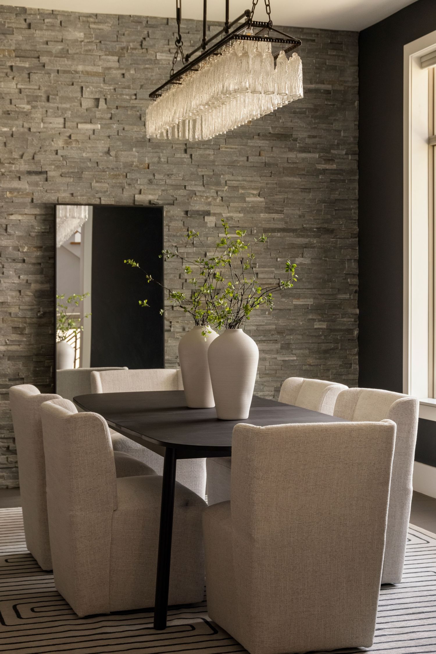 Modern dining space with stone walls, contemporary furniture, and crystal lighting fixtures.