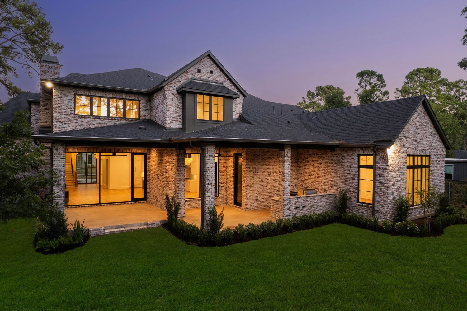 Sprawling stone estate with multiple wings and warm interior lighting at twilight.