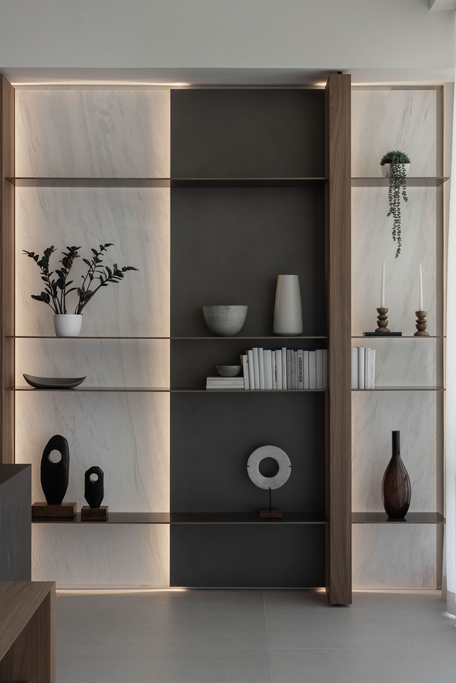 Built-in shelving unit with contrasting dark and light panels displaying minimalist decor items.