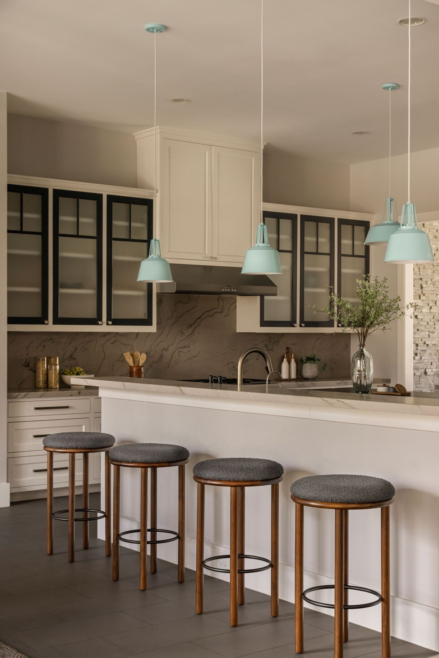 Sleek kitchen island with wooden barstools and mint pendant lights offers modern casual dining space.