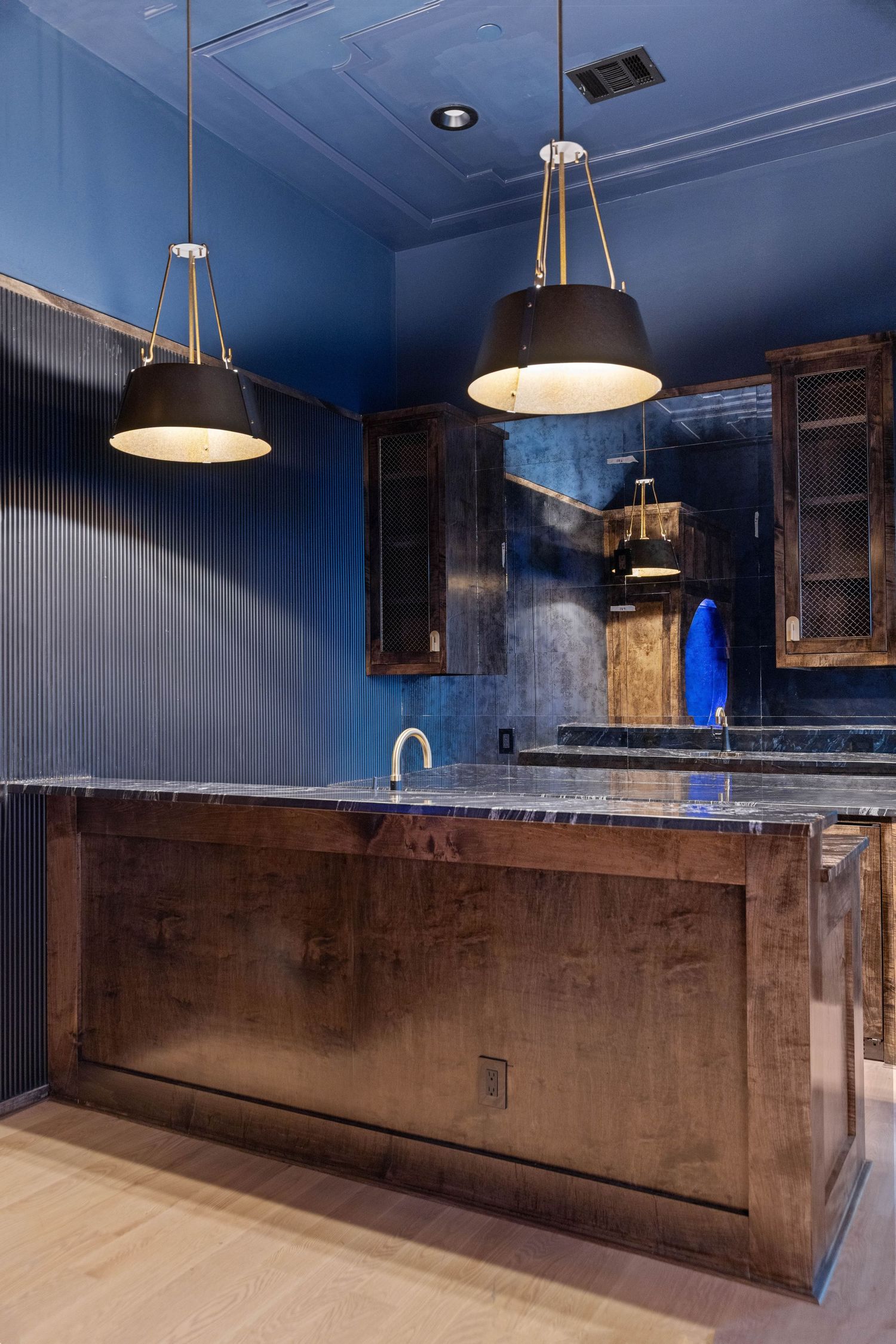 Contemporary basement bar with dark blue ceiling, pendant lighting and concrete countertops.