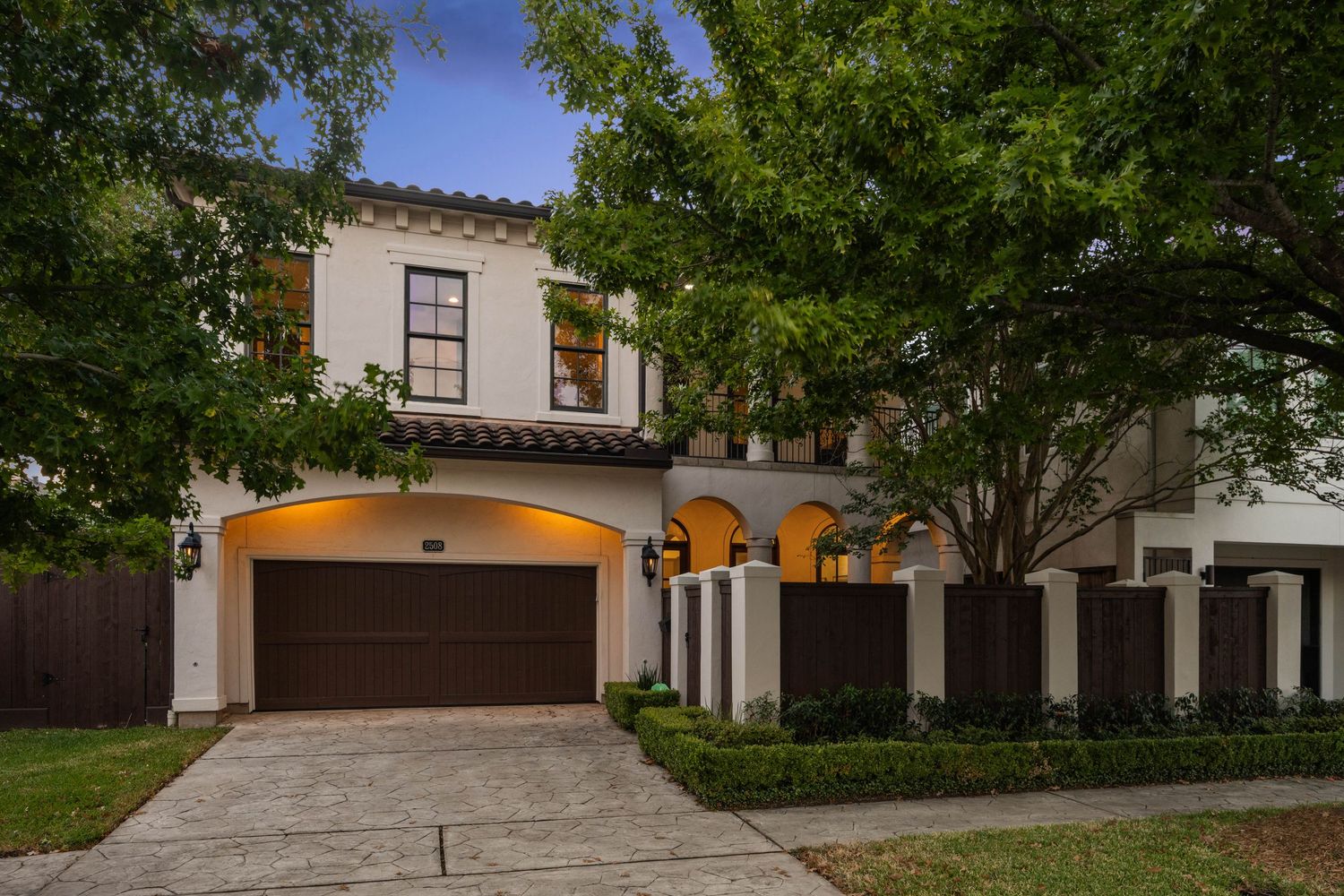 Exterior view of large Mediterranean-style home with multi-car garage and mature landscaping.