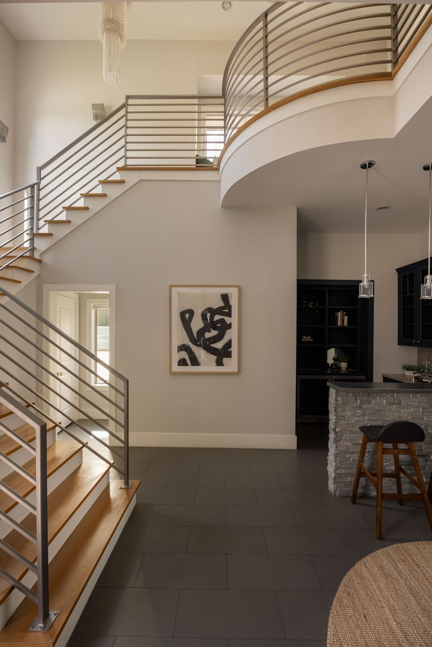 Modern interior space with curved staircase featuring metal railings and wooden steps.