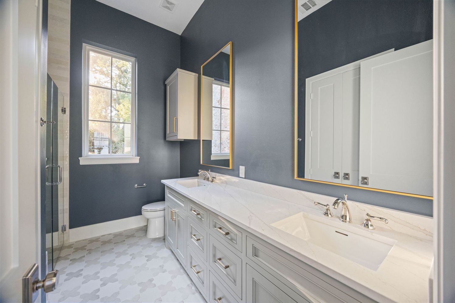 Luxurious white bathroom with navy blue walls, dual vanity, and large windows.