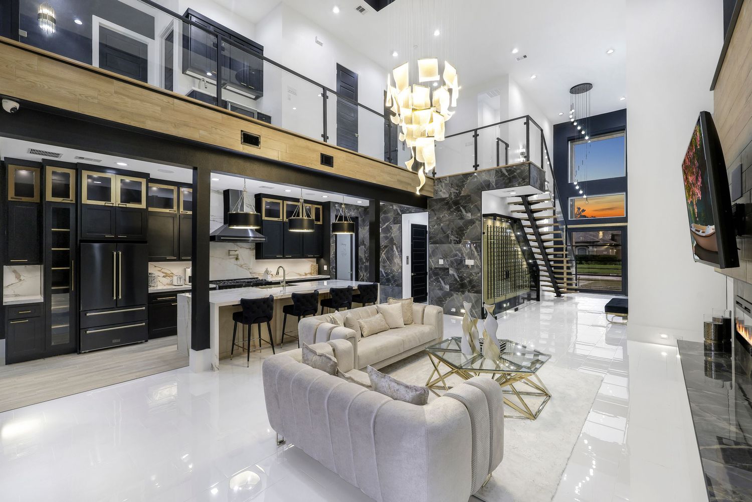 Modern living area with high ceilings, floating staircase, and contemporary chandelier in white and black finishes.
