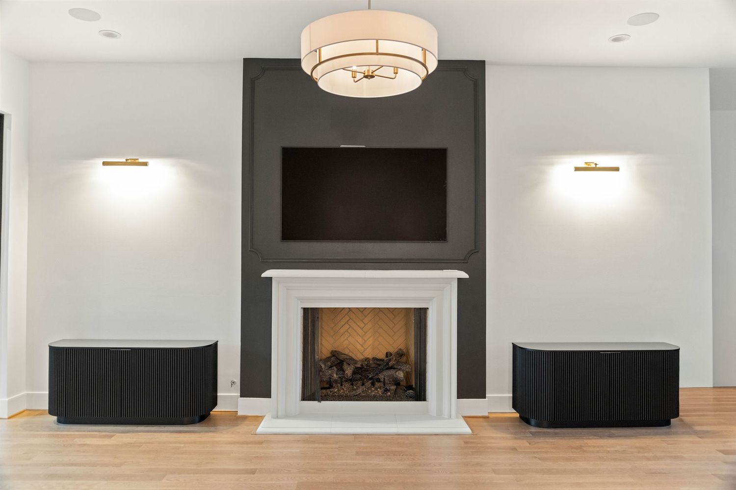 White living room with recessed lighting, crown molding, and wall-mounted TV above fireplace.