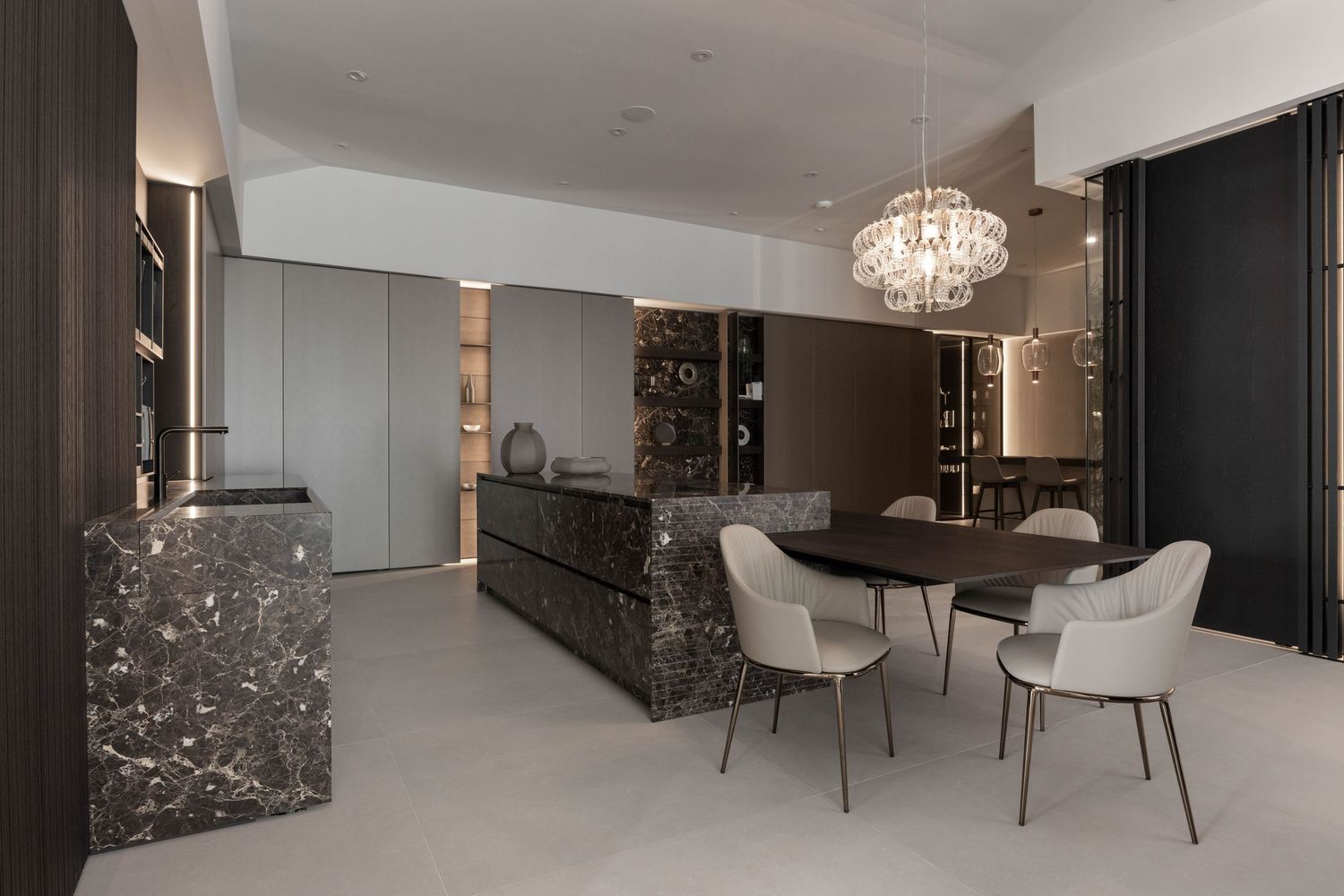 Sophisticated dining area with crystal chandelier and modern kitchen integration.