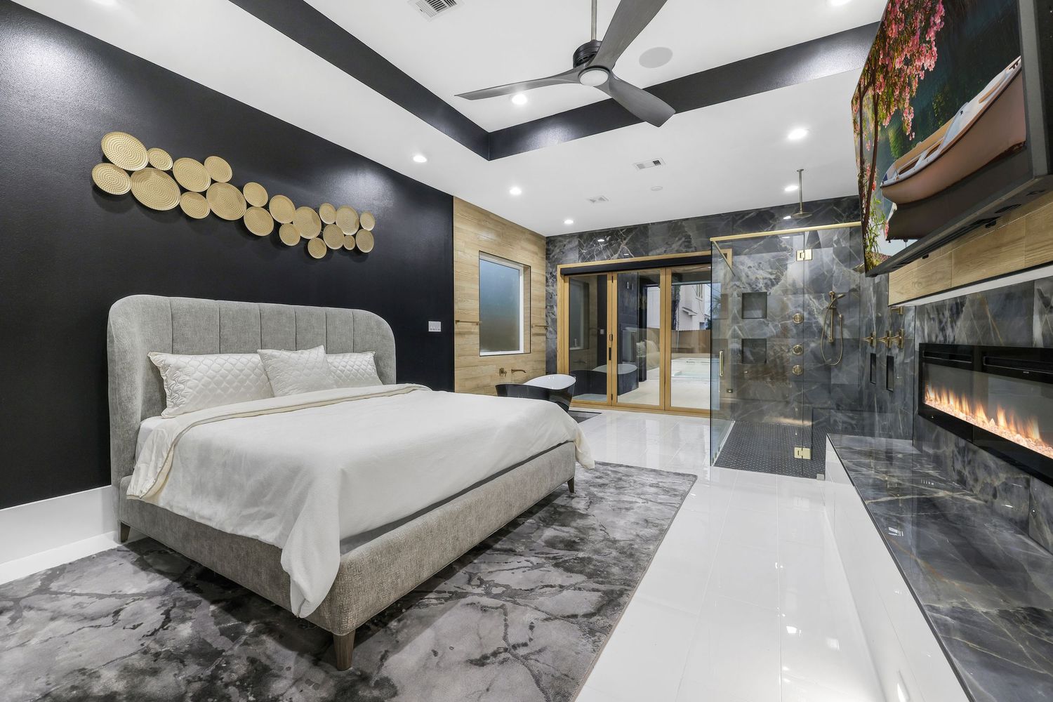 Contemporary bedroom with dark marble floors, built-in fireplace, and metallic wall art.