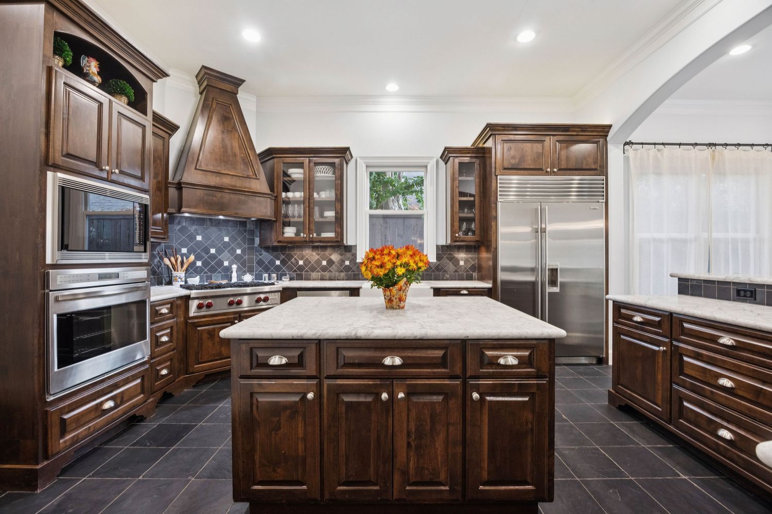 Modern white kitchen with dark wood cabinets, stainless appliances and large center island.