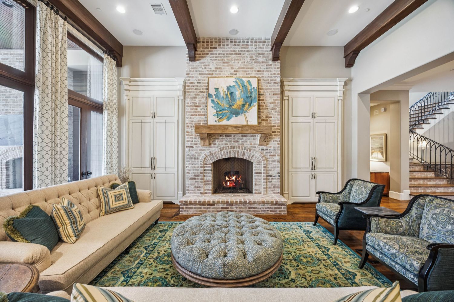 Spacious living room featuring brick accents, wooden beams, and plush seating arrangements.