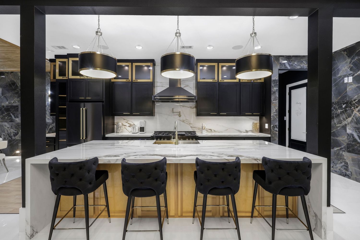 Luxurious black and white kitchen featuring marble backsplash and modern bar seating.