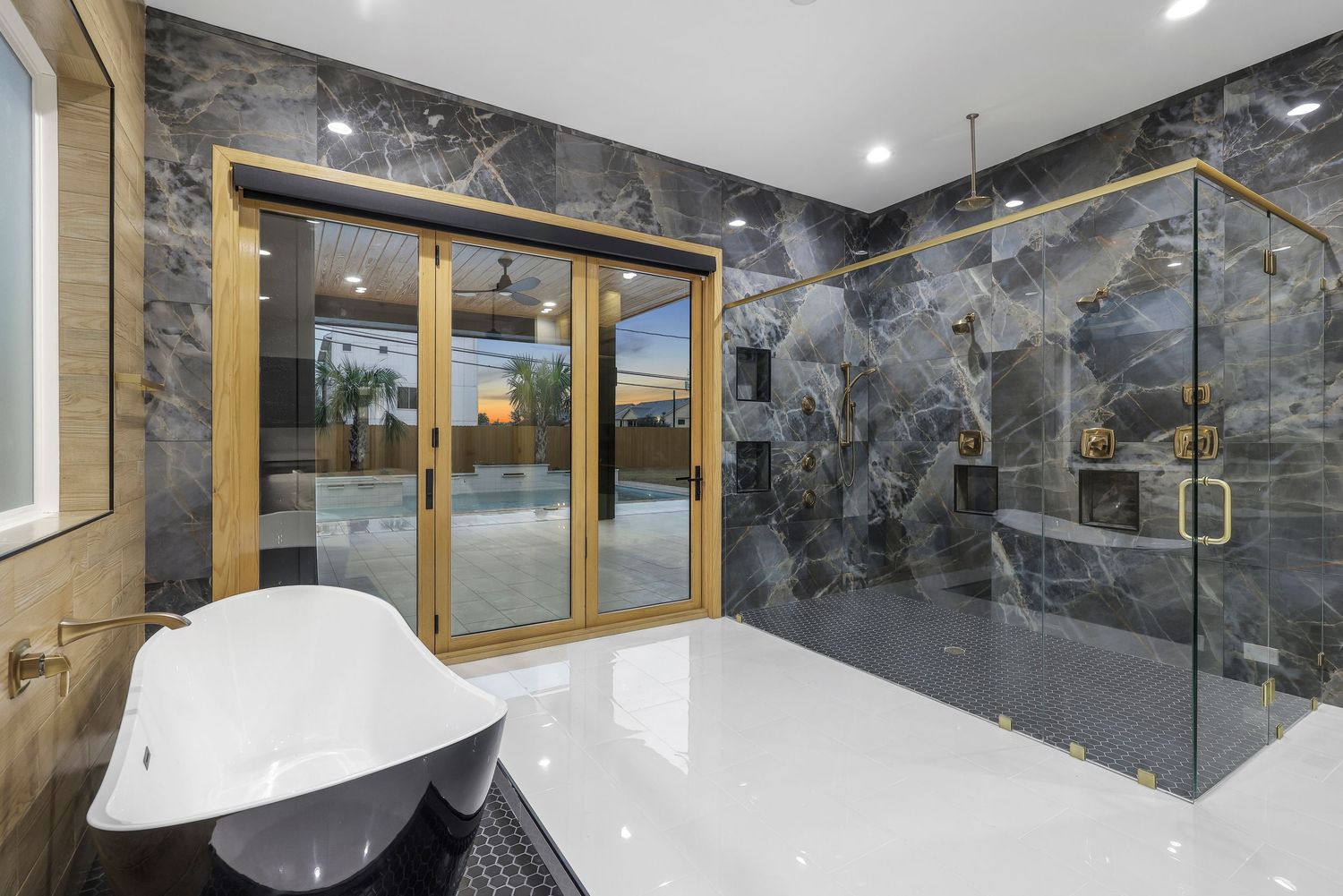Luxurious bathroom featuring a freestanding tub and glass shower with dramatic black marble walls.